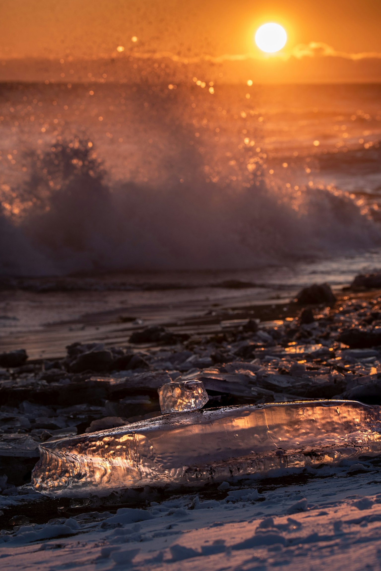 Atardecer sobre el océano con olas salpicando en la costa rocosa