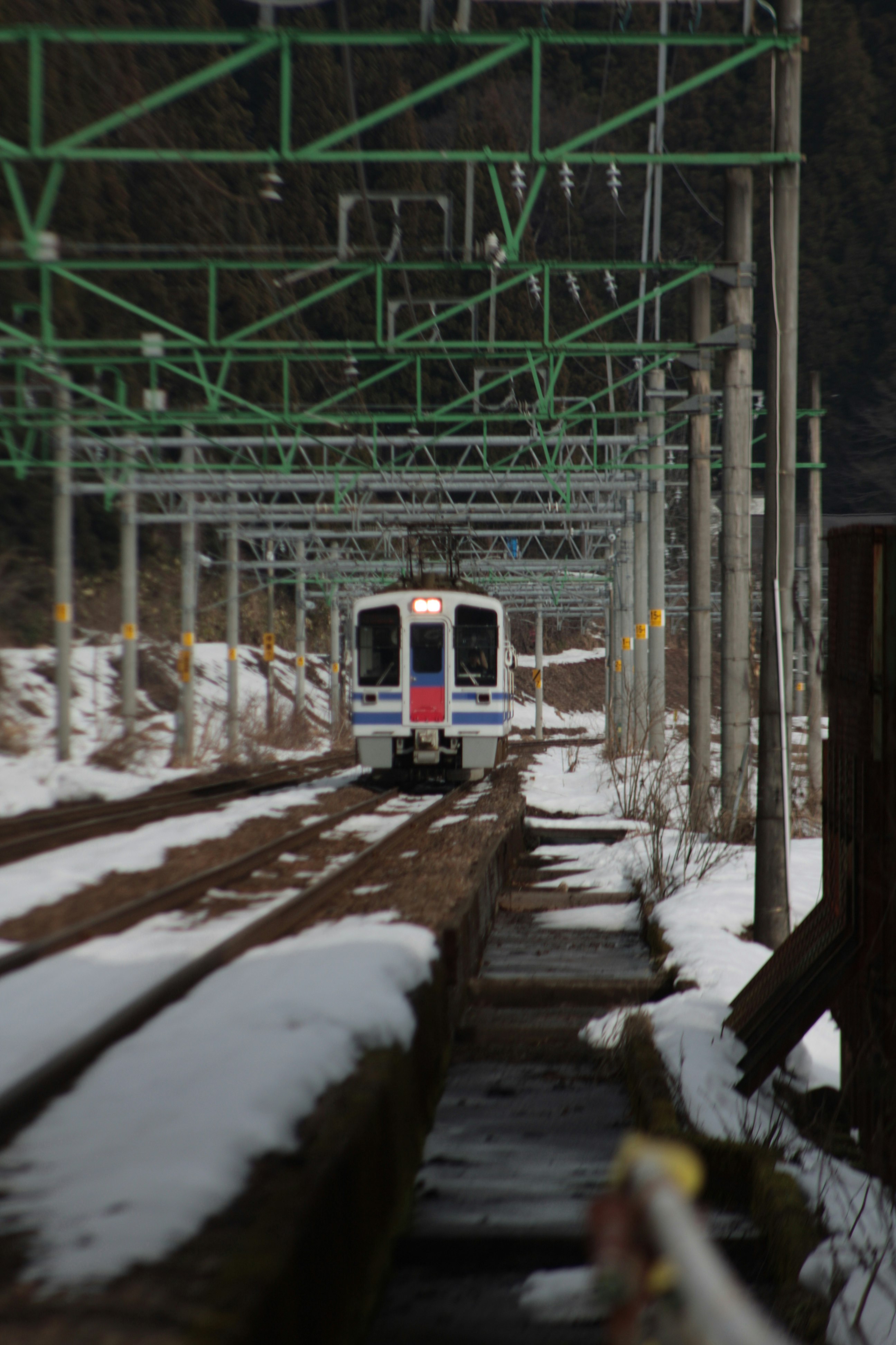train running on snowy tracks under an elevated structure