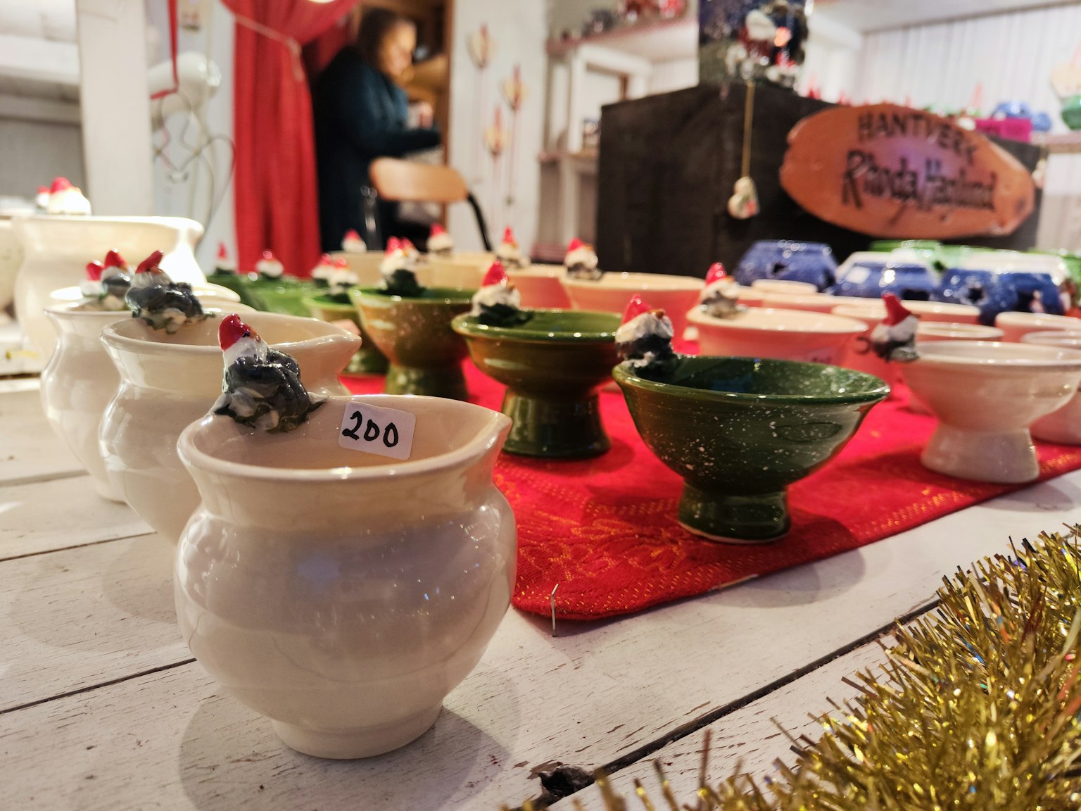 Exhibición de cuencos de cerámica con decoraciones de sombreros de Santa en un mercado festivo