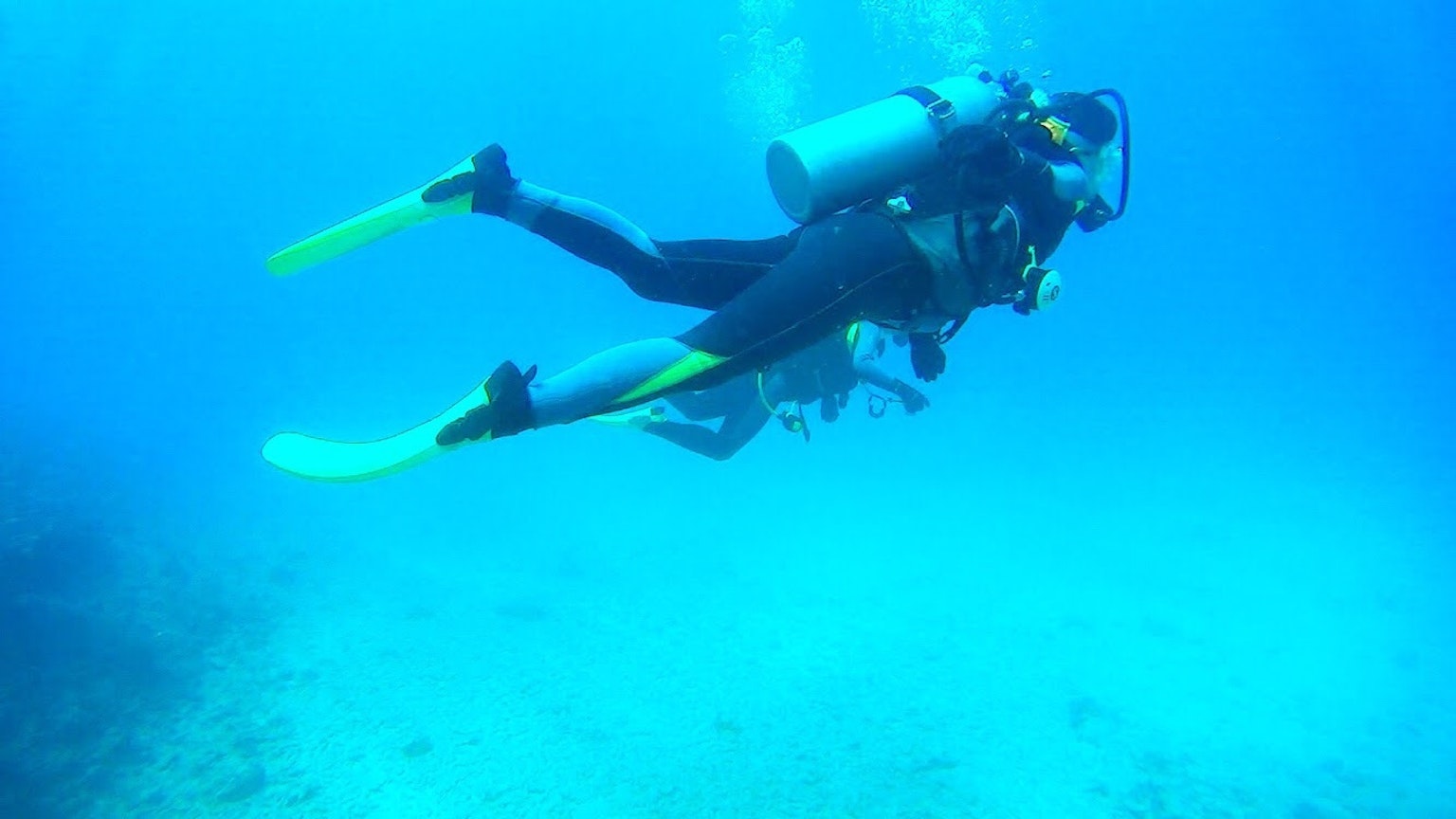 Penyelam yang berenang di bawah air di lautan biru