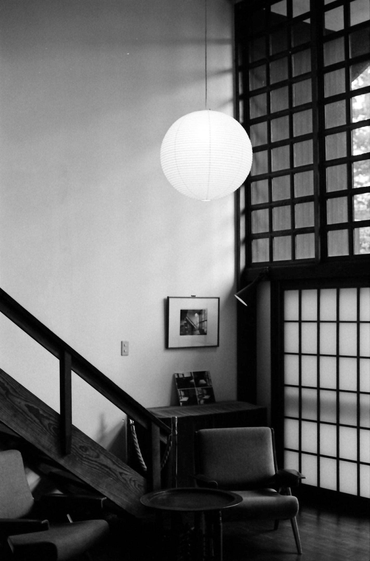 Corner of a modern living room featuring a white pendant lamp with a staircase and distinctive black window lattice