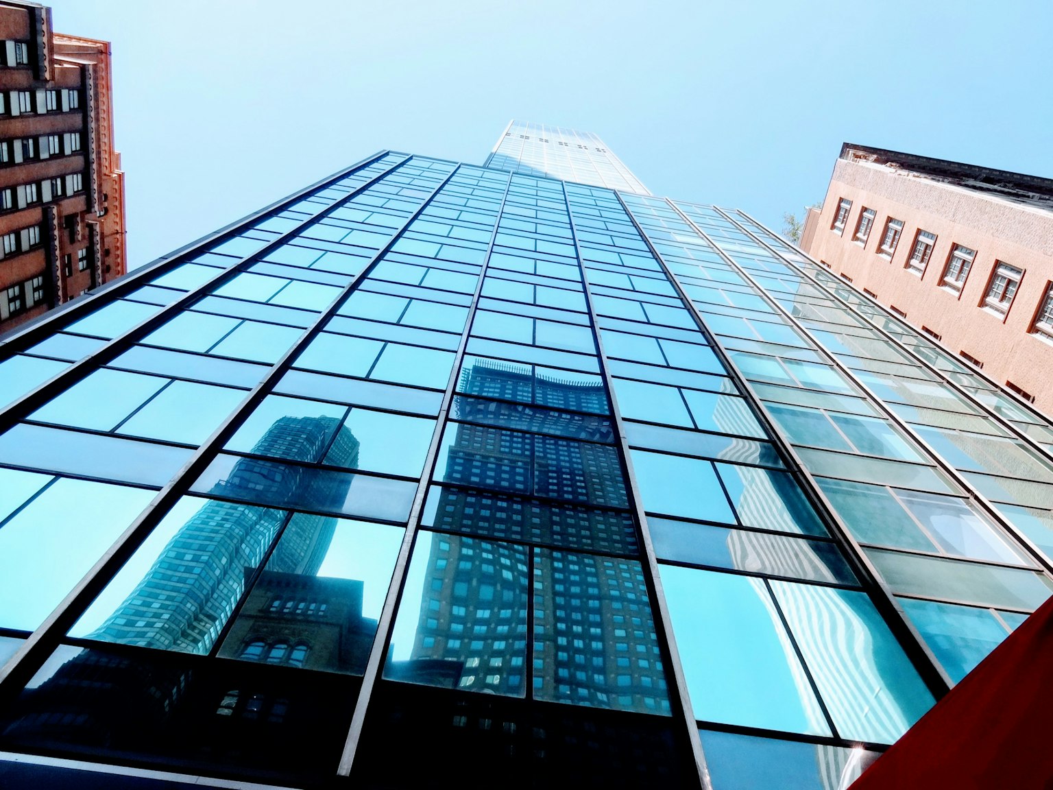 Tall building with a glass facade reflecting the blue sky