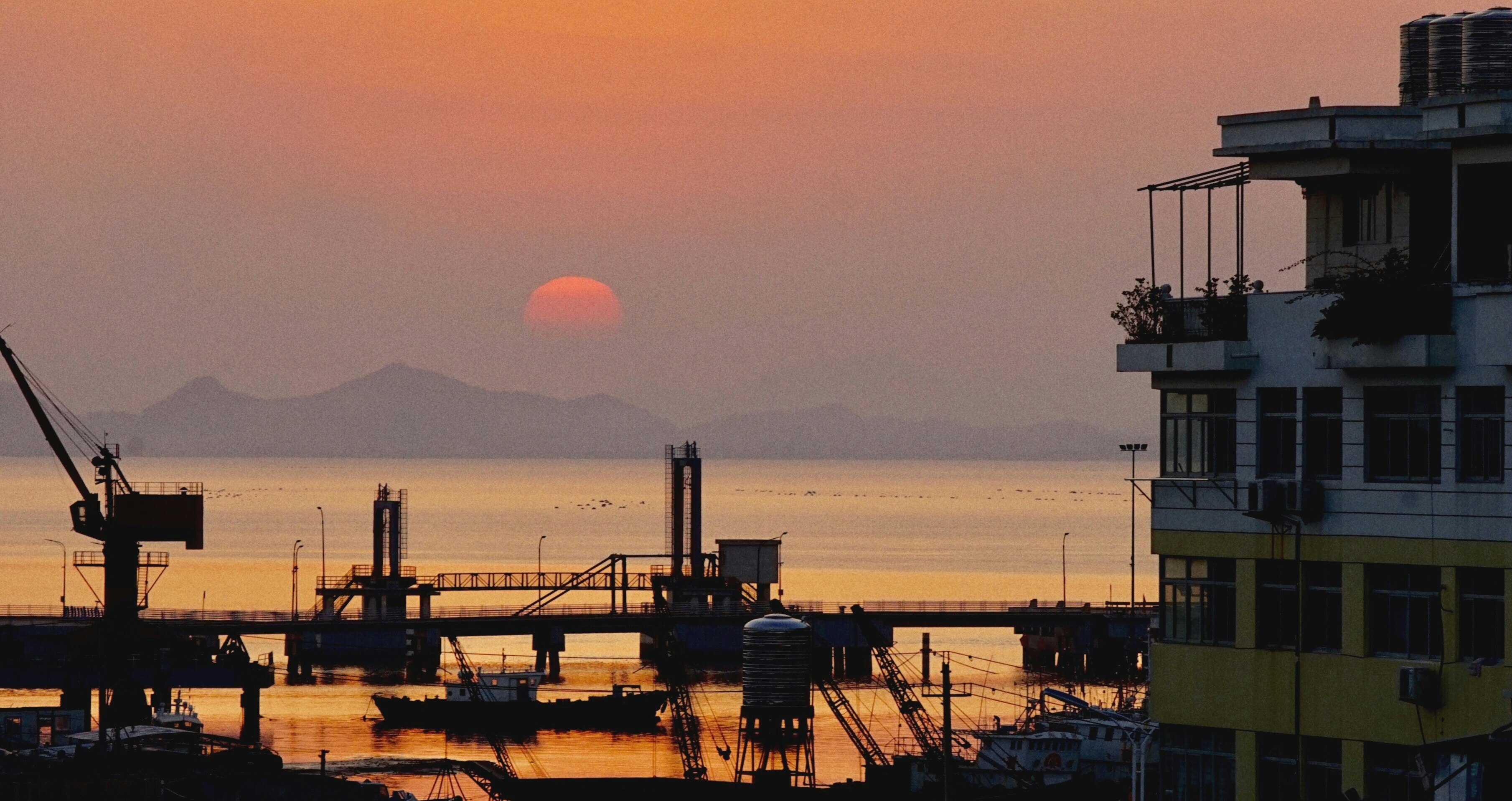 夕暮れの港と水面に沈む太陽の風景