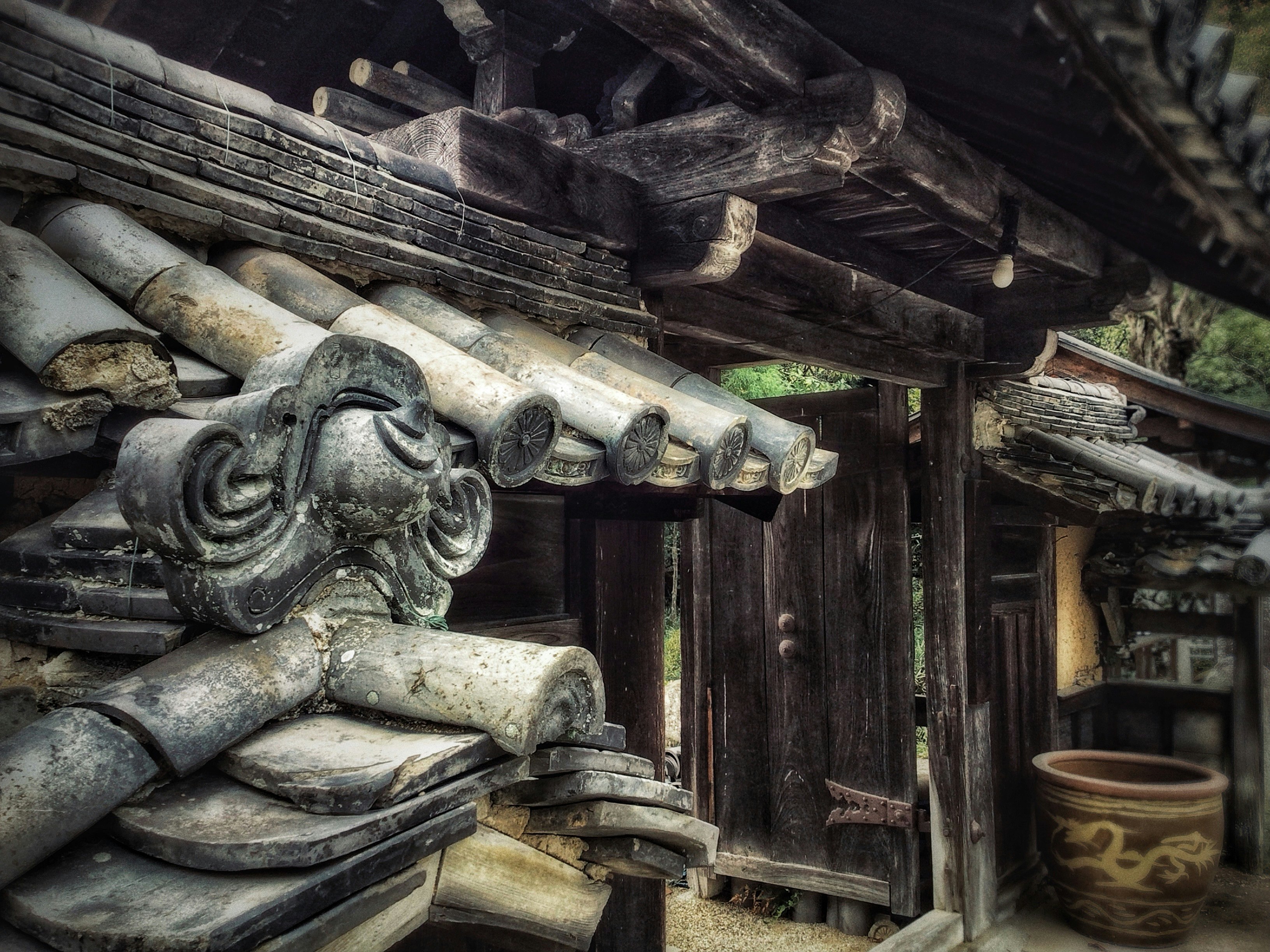 古い木造の寺の門に並ぶ瓦と土壁の装飾画像