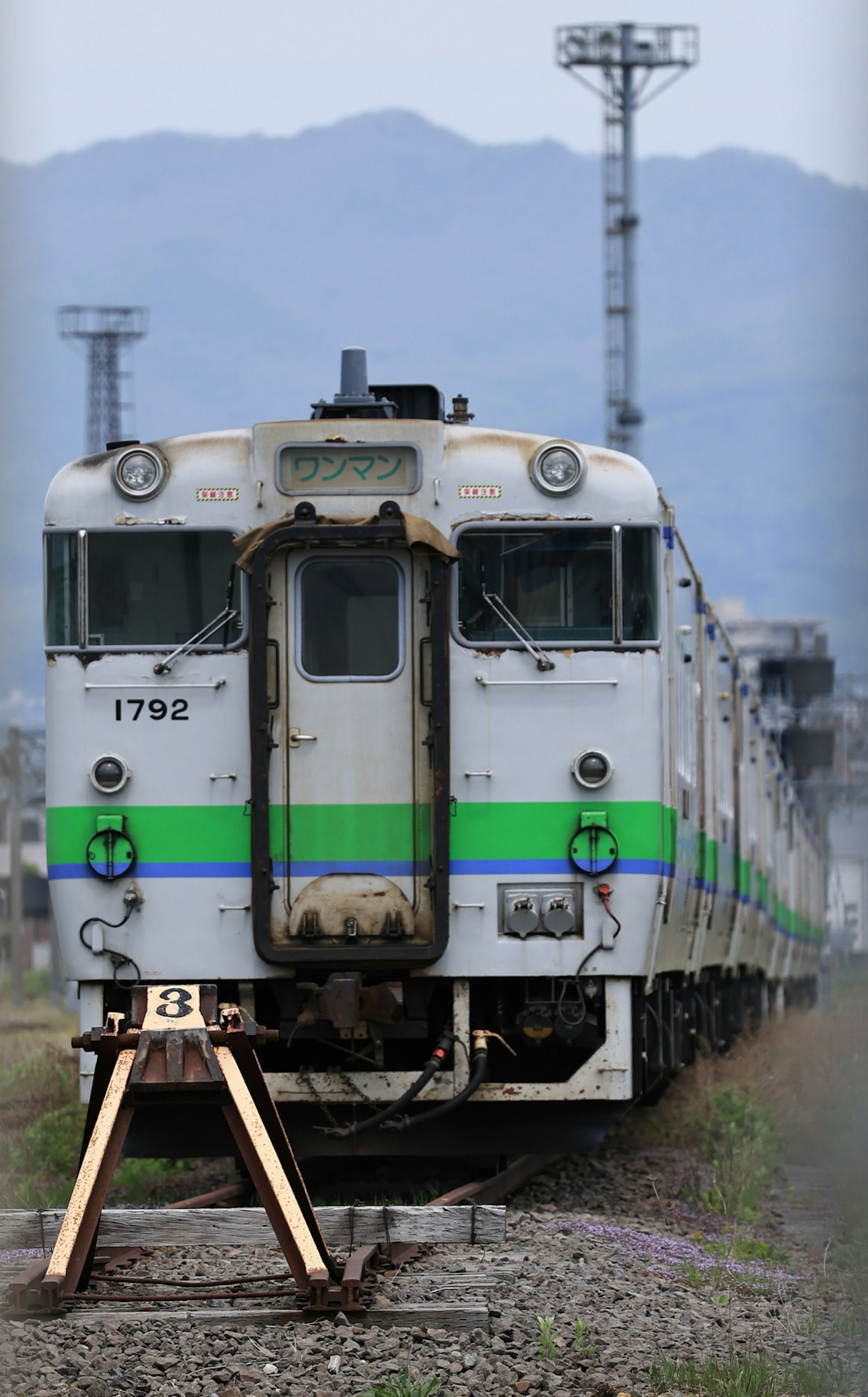 Un tren antiguo estacionado en las vías con montañas al fondo