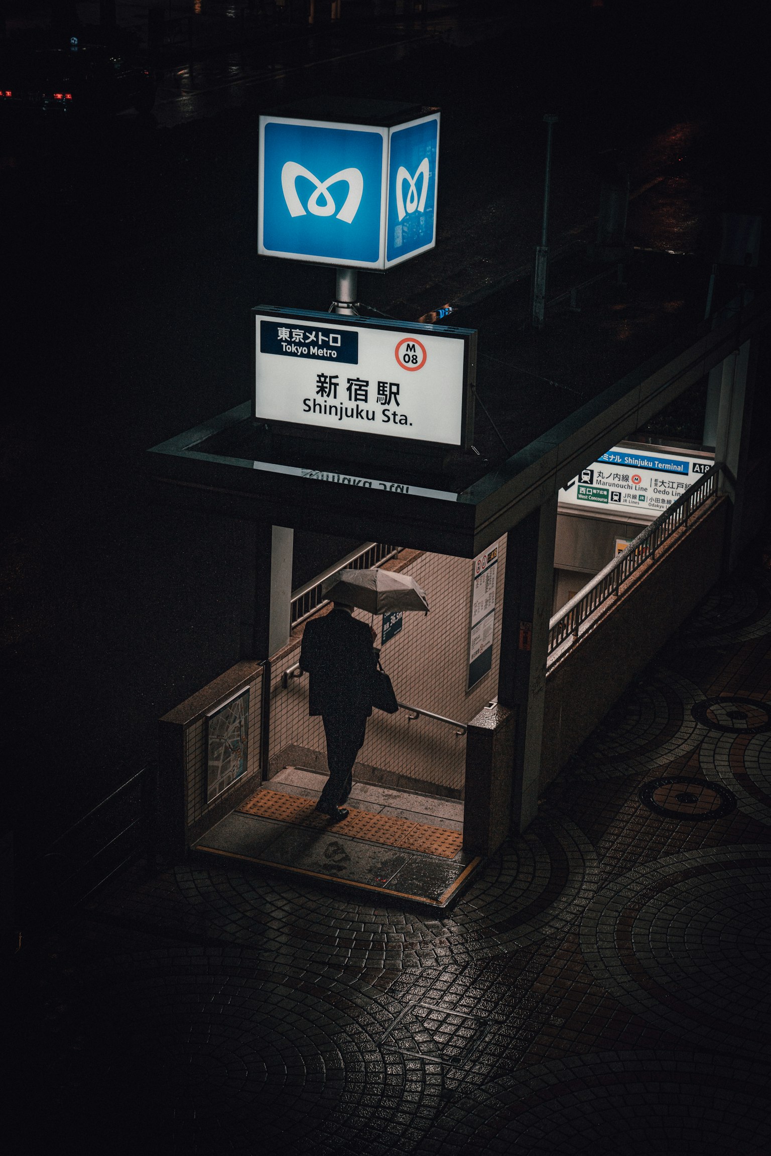 Personne marchant à l'entrée du métro avec un panneau lumineux