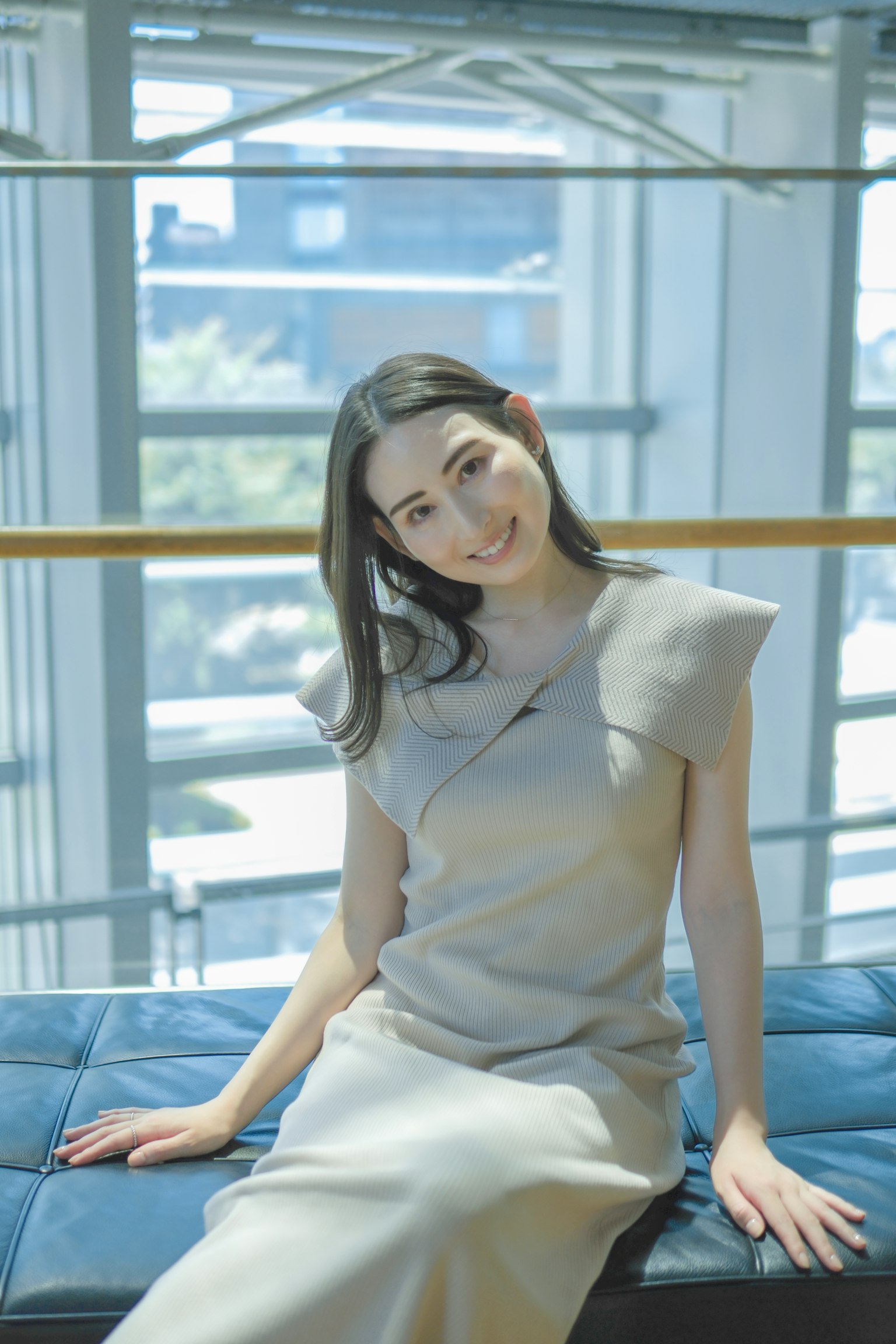 밝은 창가에서 미소짓고 있는 여성의 초상, 간단한 디자인의 드레스를 입고 있음