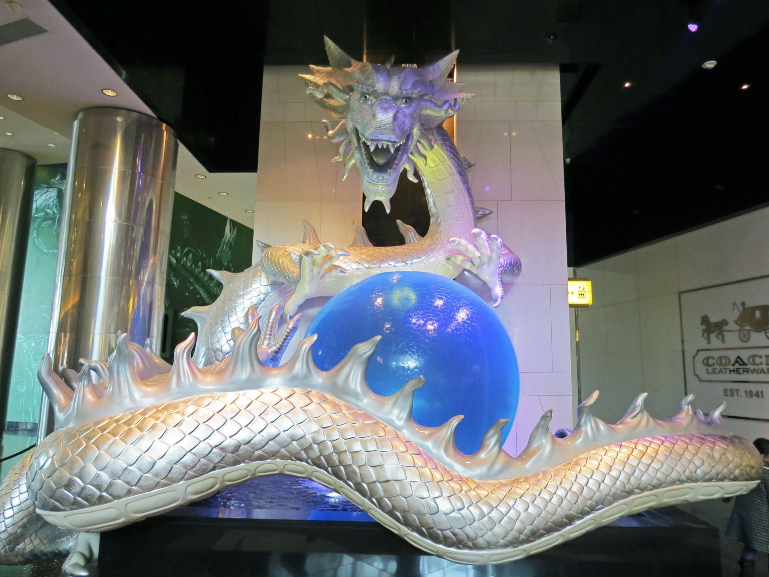 Sculpture of a silver dragon atop a blue orb