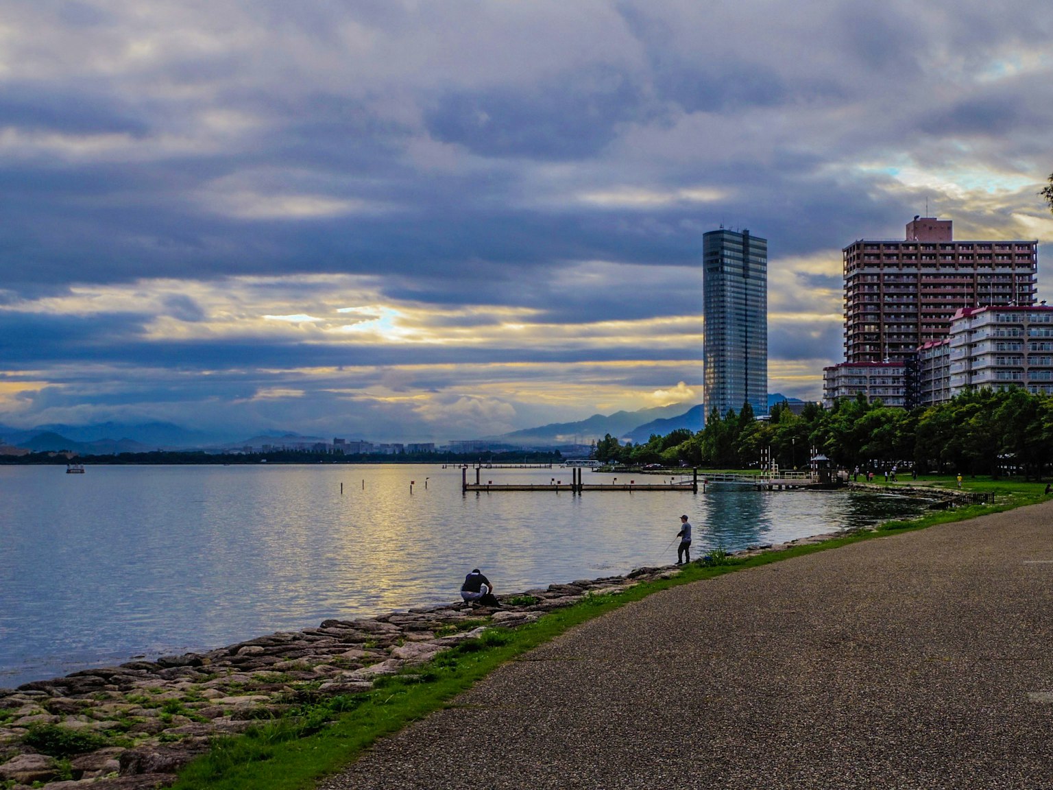 Scenic waterfront park with tall buildings and cloudy sky