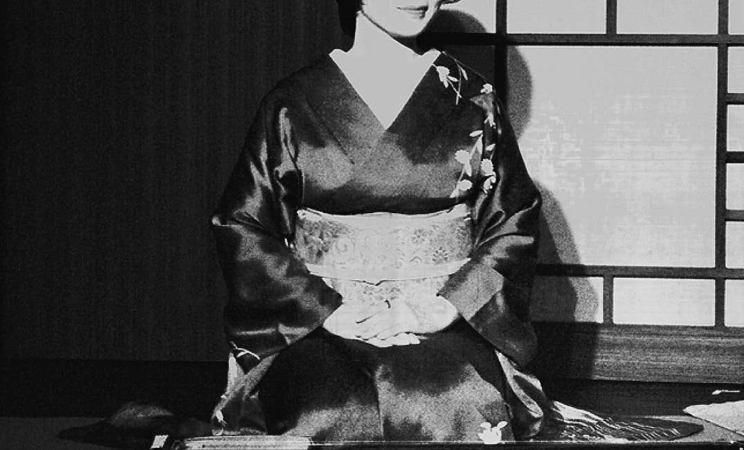 着物姿の女性が座っている室内のモノクロ画像