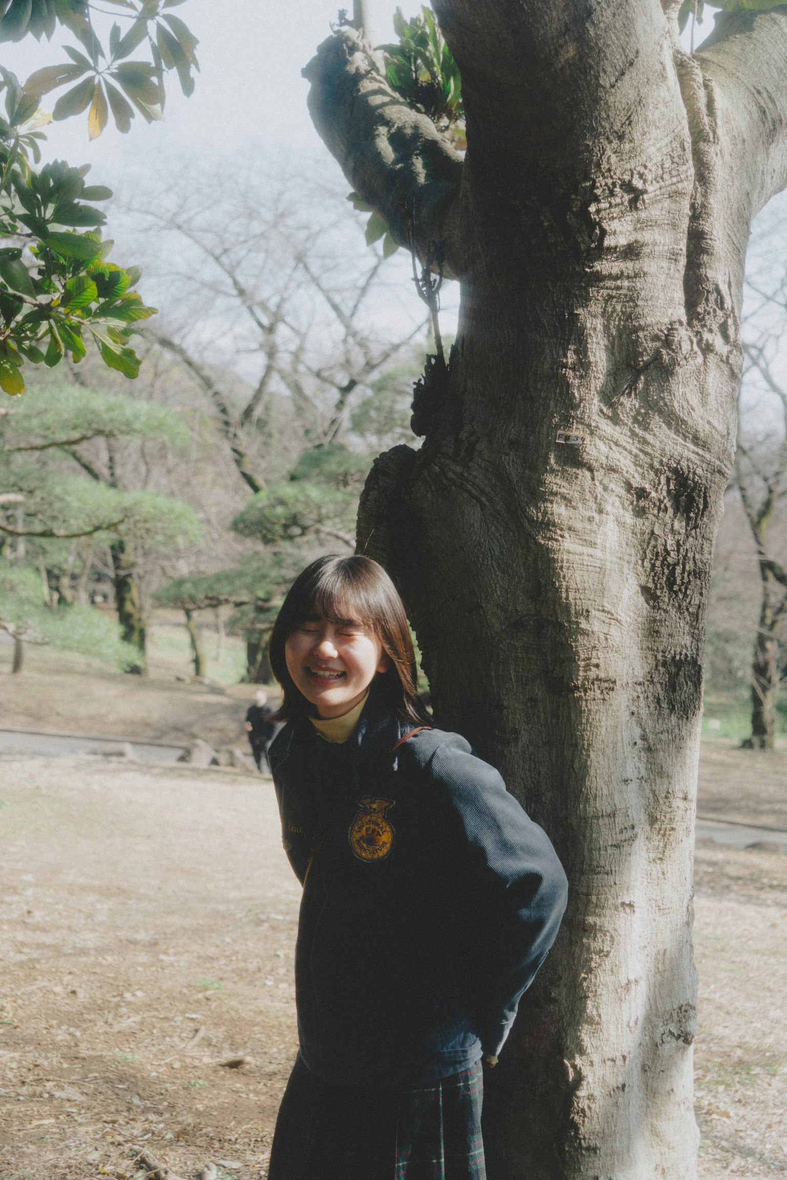 Joven mujer sonriente de pie junto a un árbol