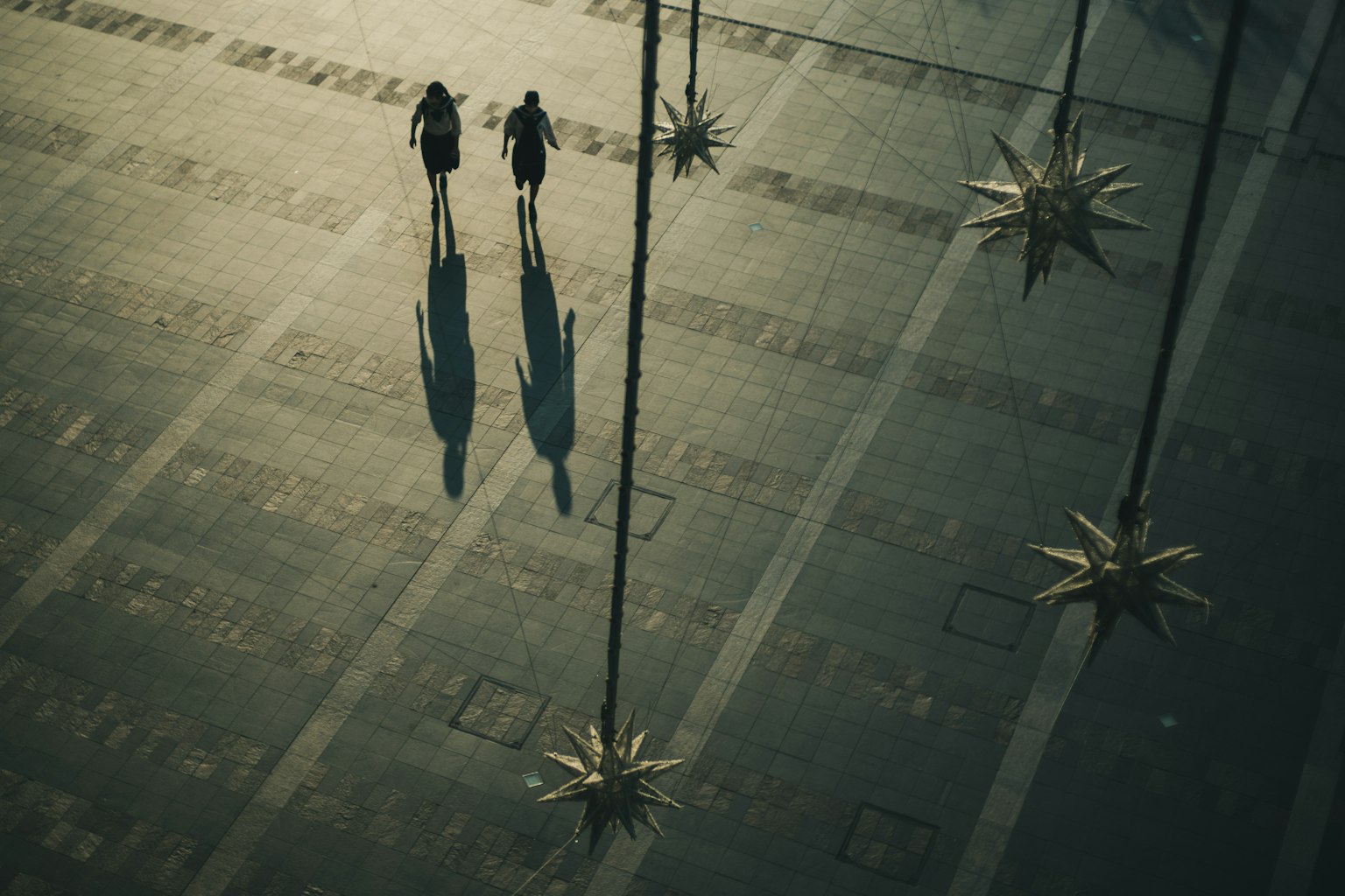 Zwei Personen, die gehen und Schatten werfen, umgeben von sternförmigen Objekten