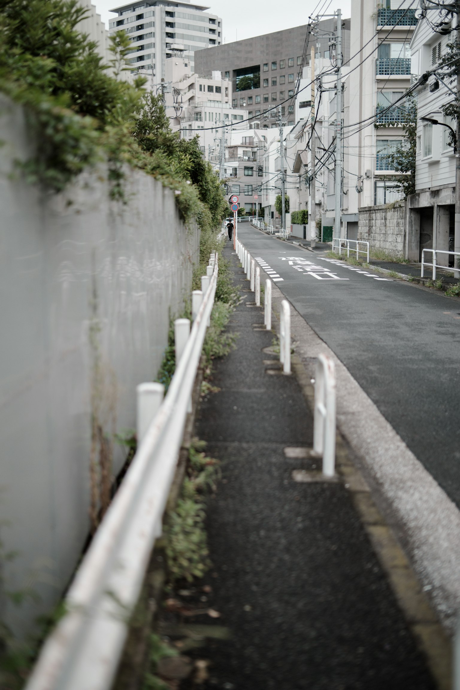 ทางเท้แคบที่มีรั้วสีขาวอยู่ตามถนนในเมืองที่เงียบสงบ