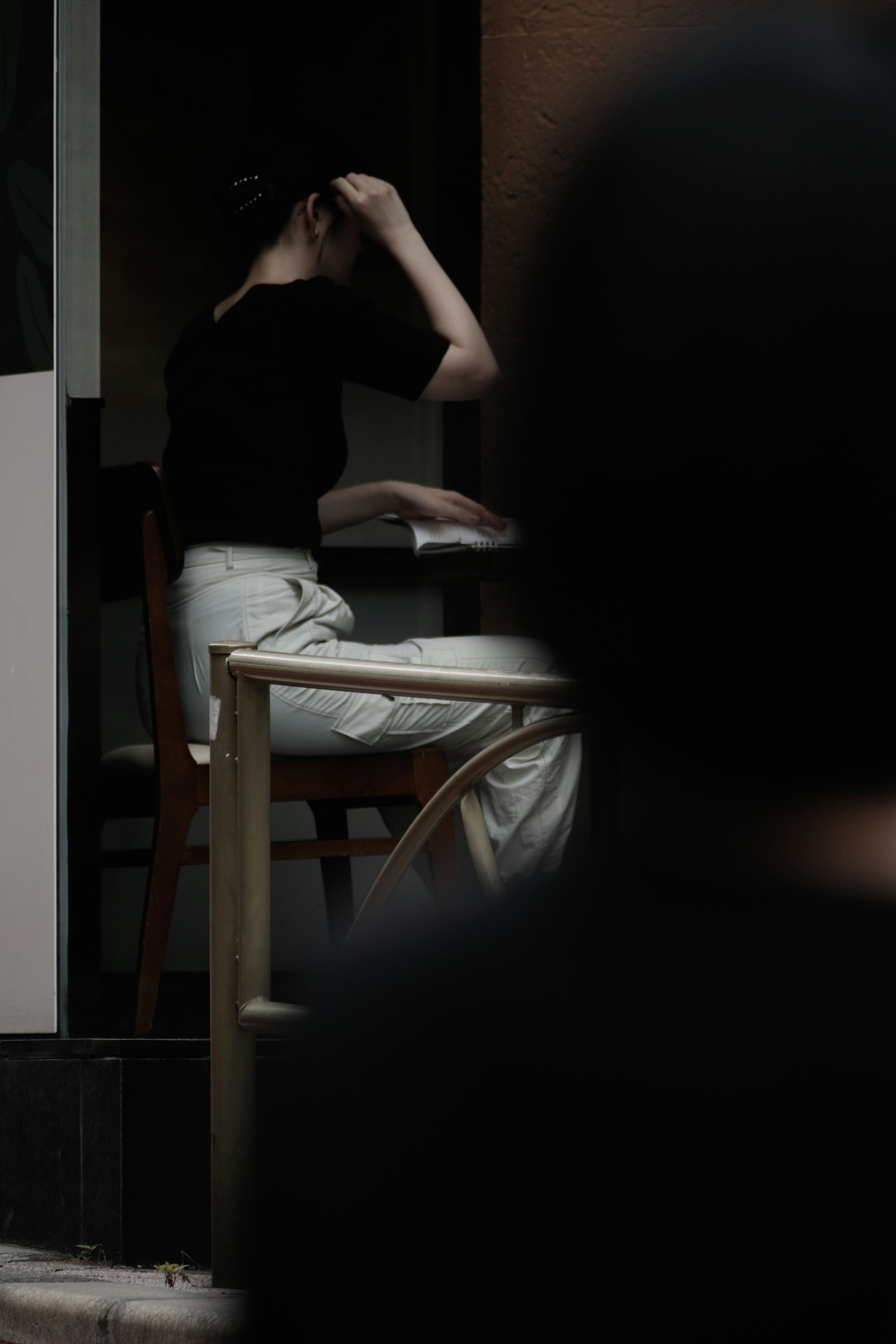 어두운 카페에 앉아 있는 여성의 손이 머리에 있는 모습