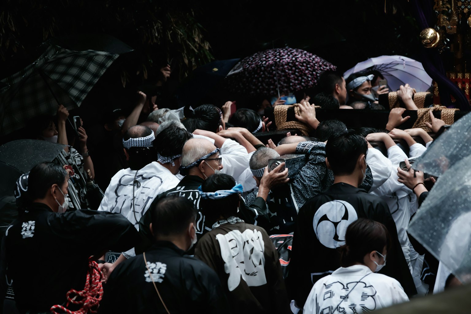 Kerumunan orang yang berpartisipasi dalam festival dengan payung di bawah hujan