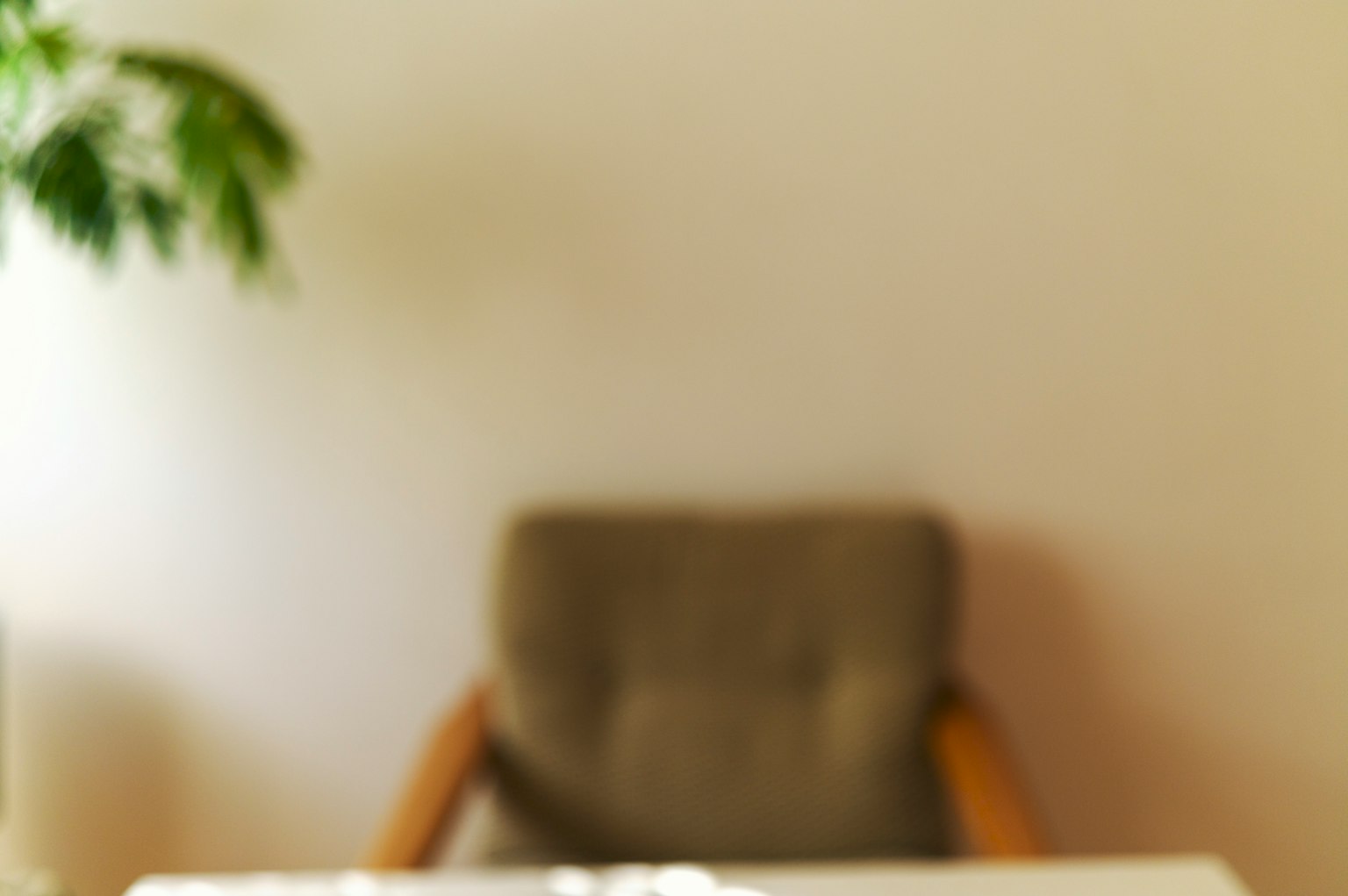 Verschwommener Hintergrund mit einer Pflanze und einem Stuhl in einem einfachen Innenraum