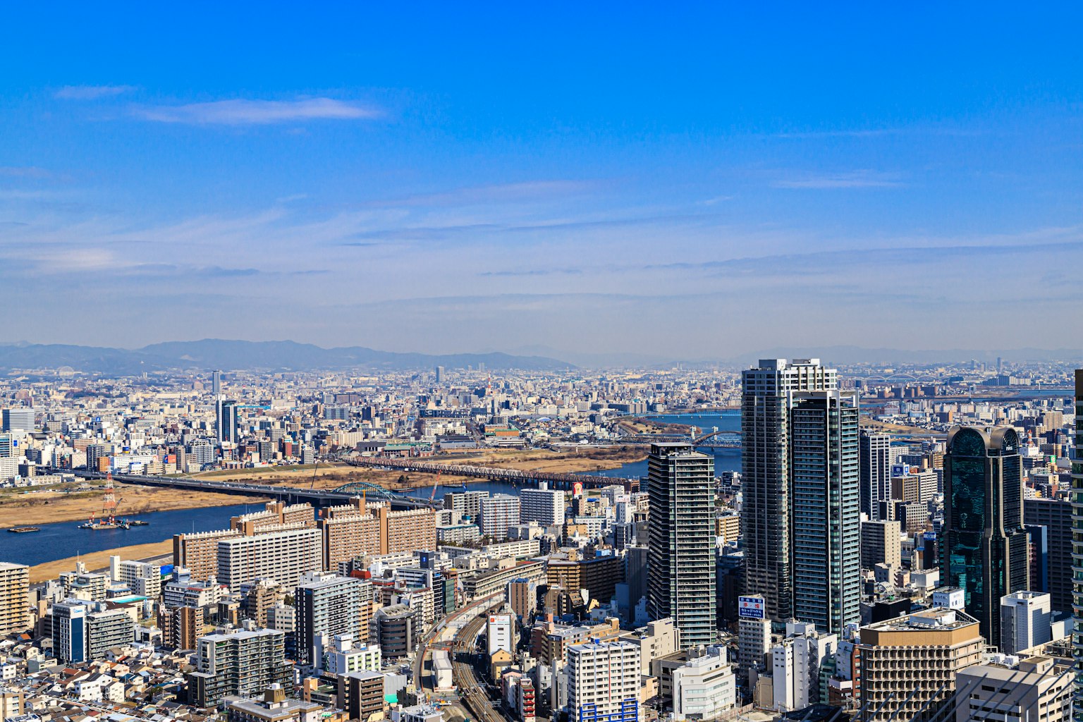 Vista panorámica de una ciudad bajo un cielo azul con rascacielos y un río