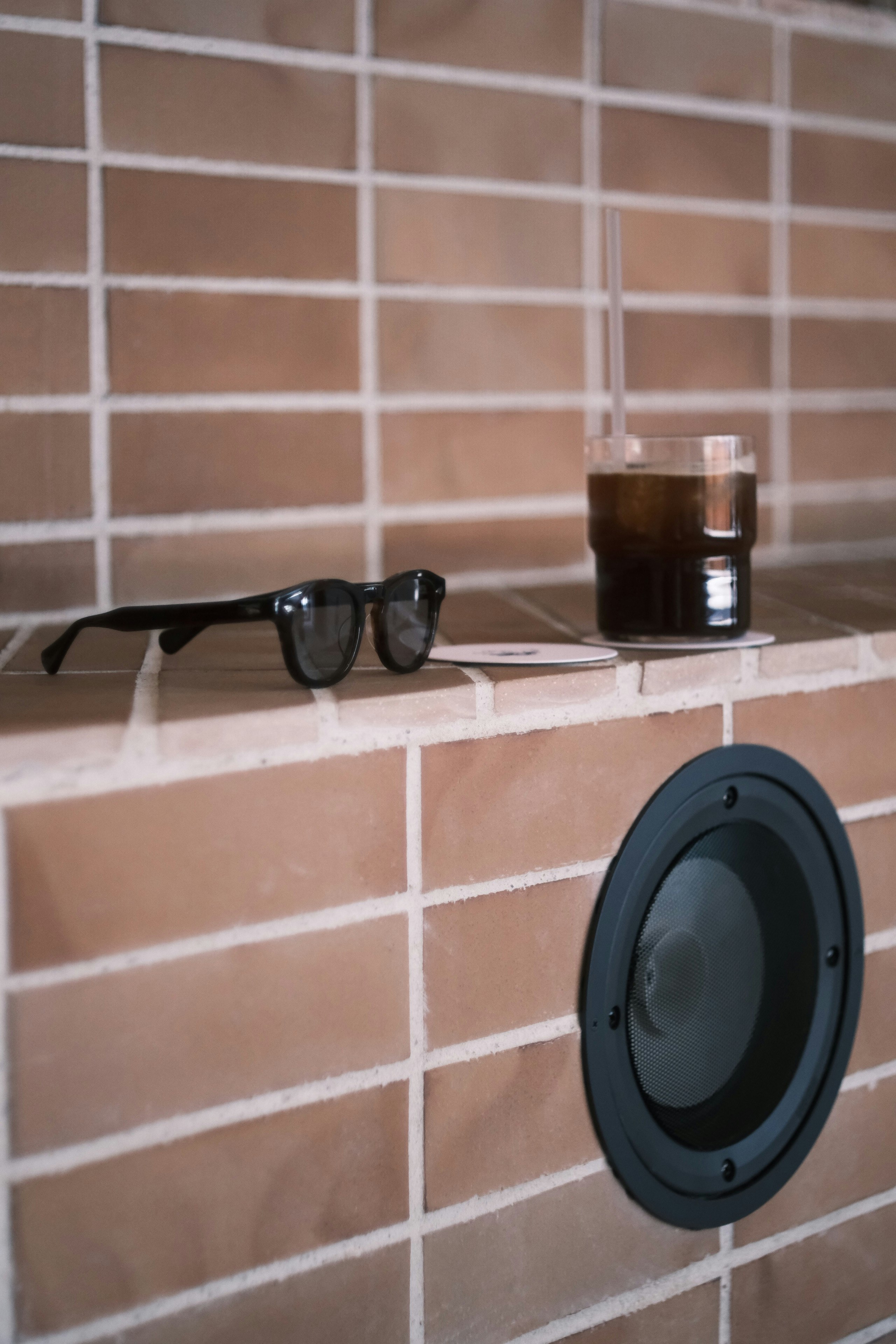 磁磚牆面置物架上的咖啡杯與玻璃杯、眼鏡