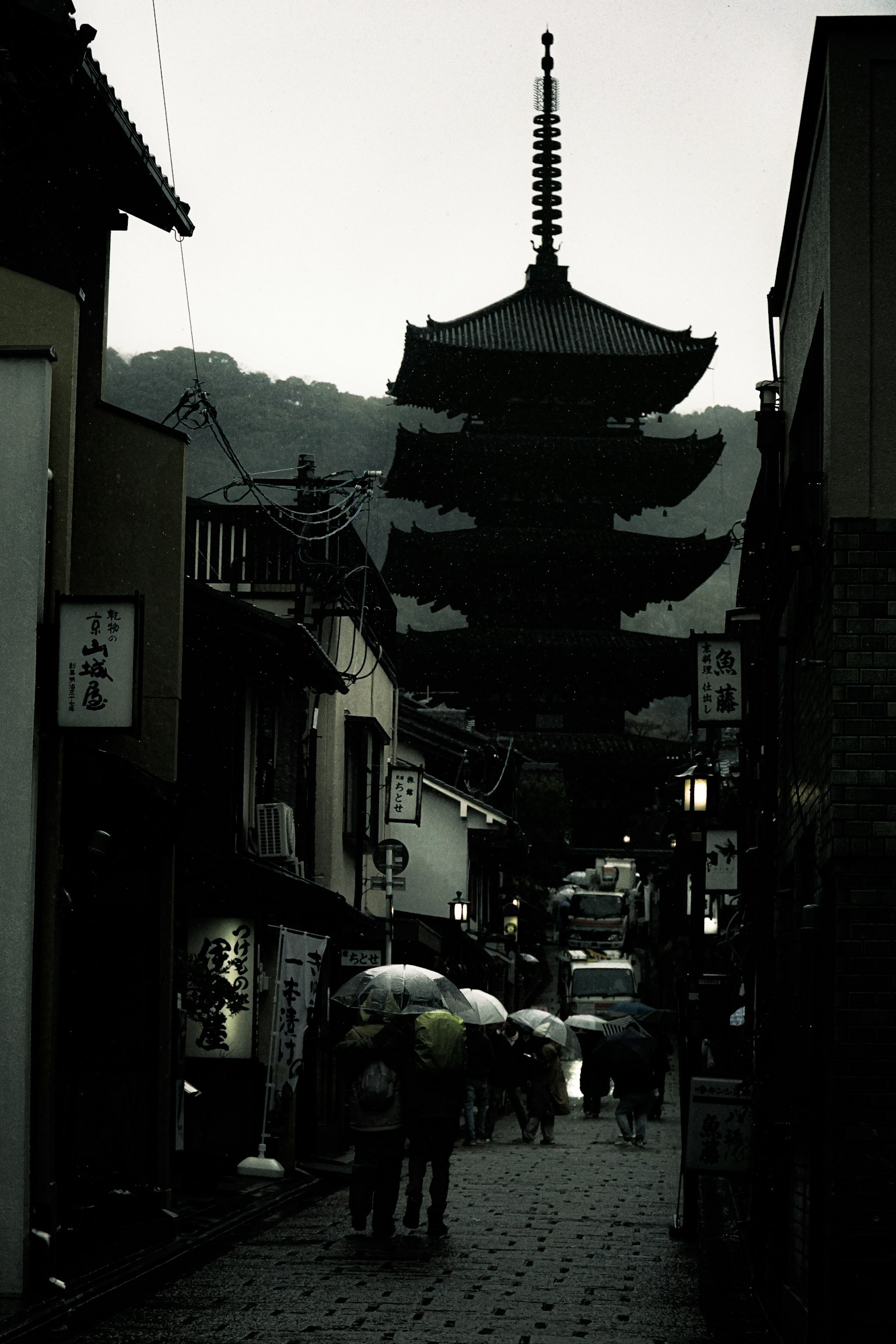 Silhouette of a pagoda amidst a rainy street scene