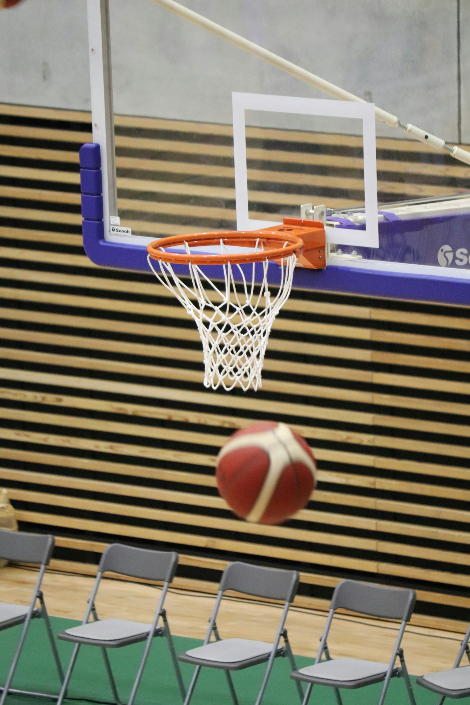 Un pallone da basket che vola verso il canestro in un palazzetto