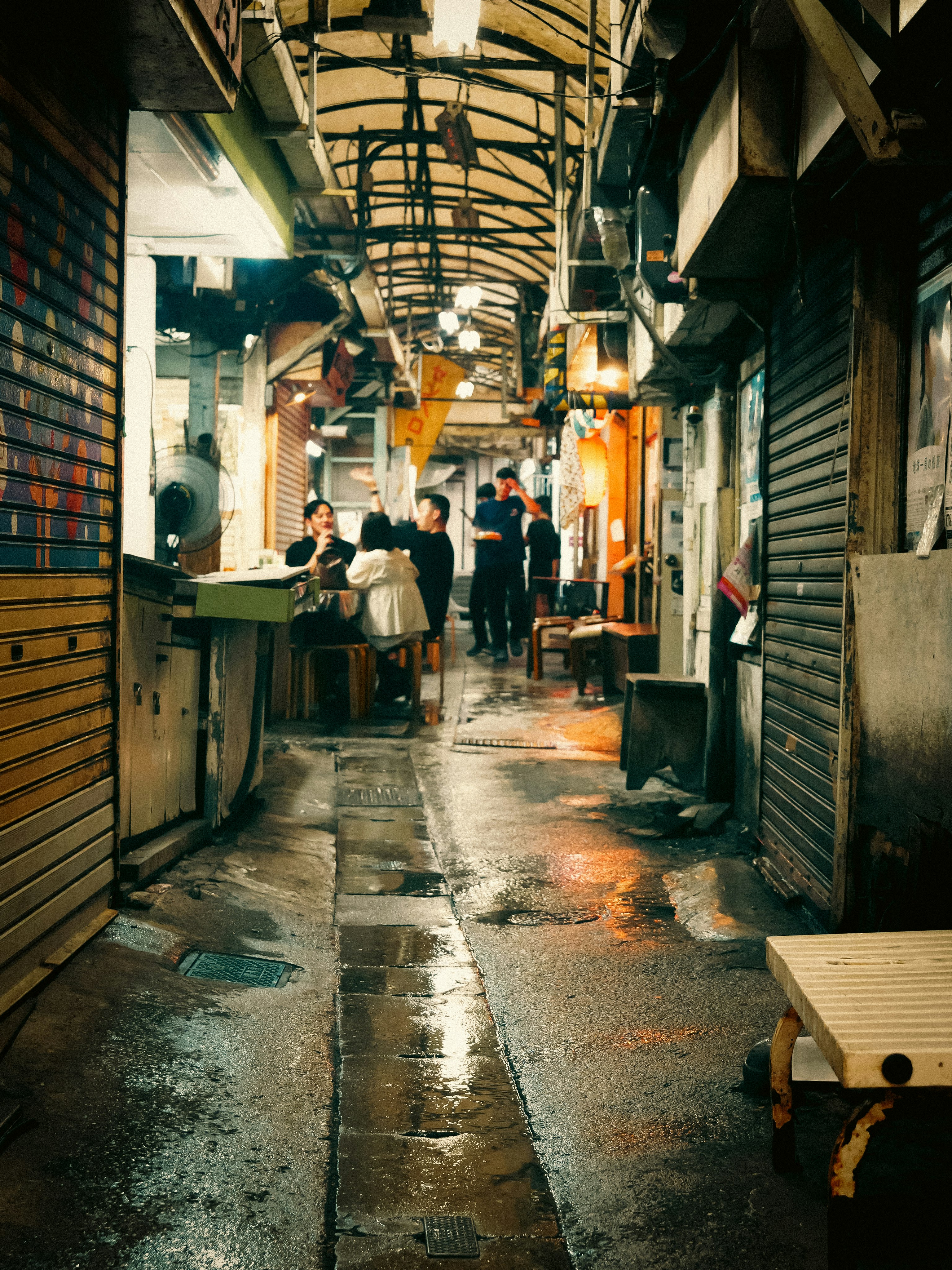 雨上がりの路地で並ぶ店先と人々の気配