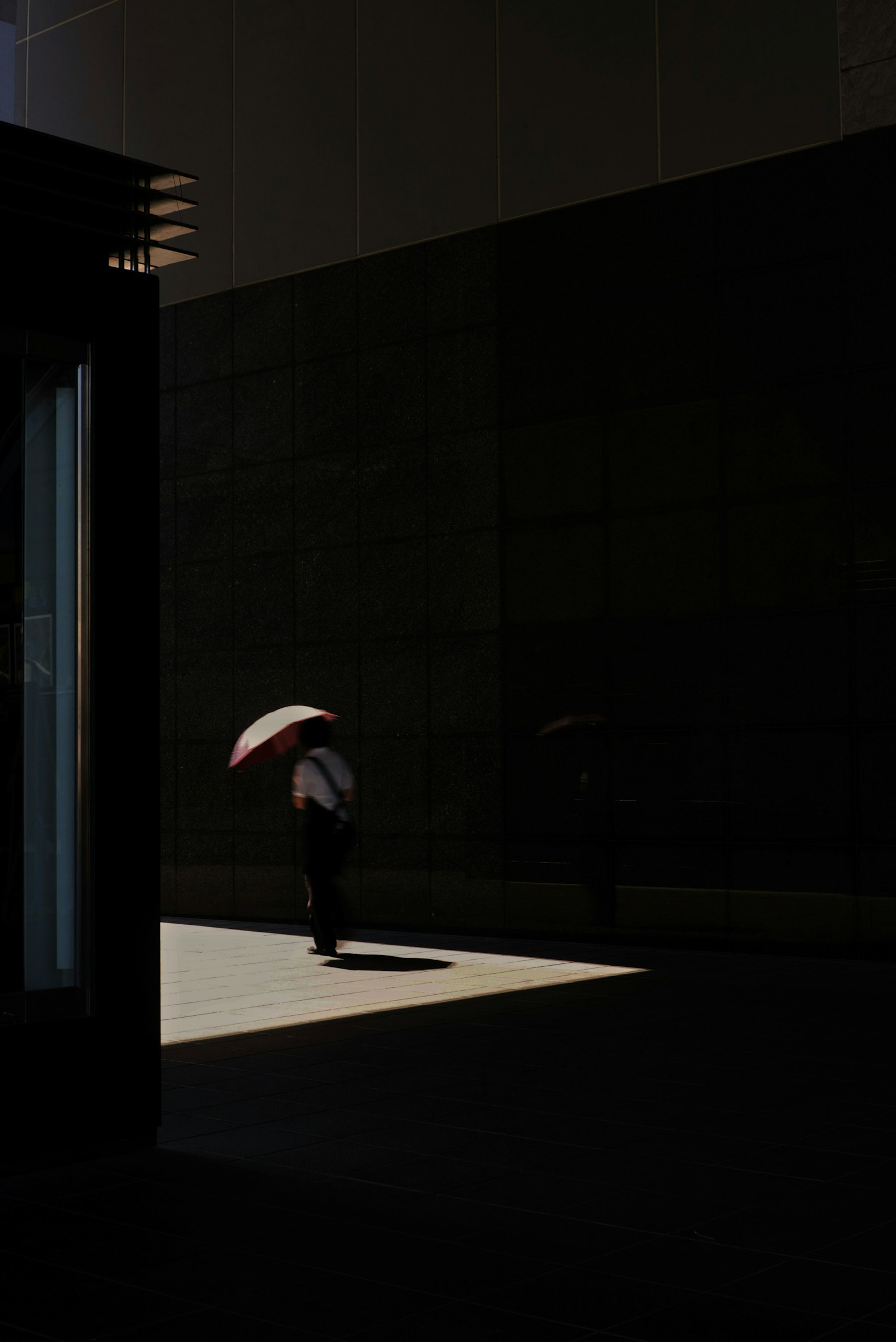Silueta de una persona con un paraguas contra un fondo oscuro