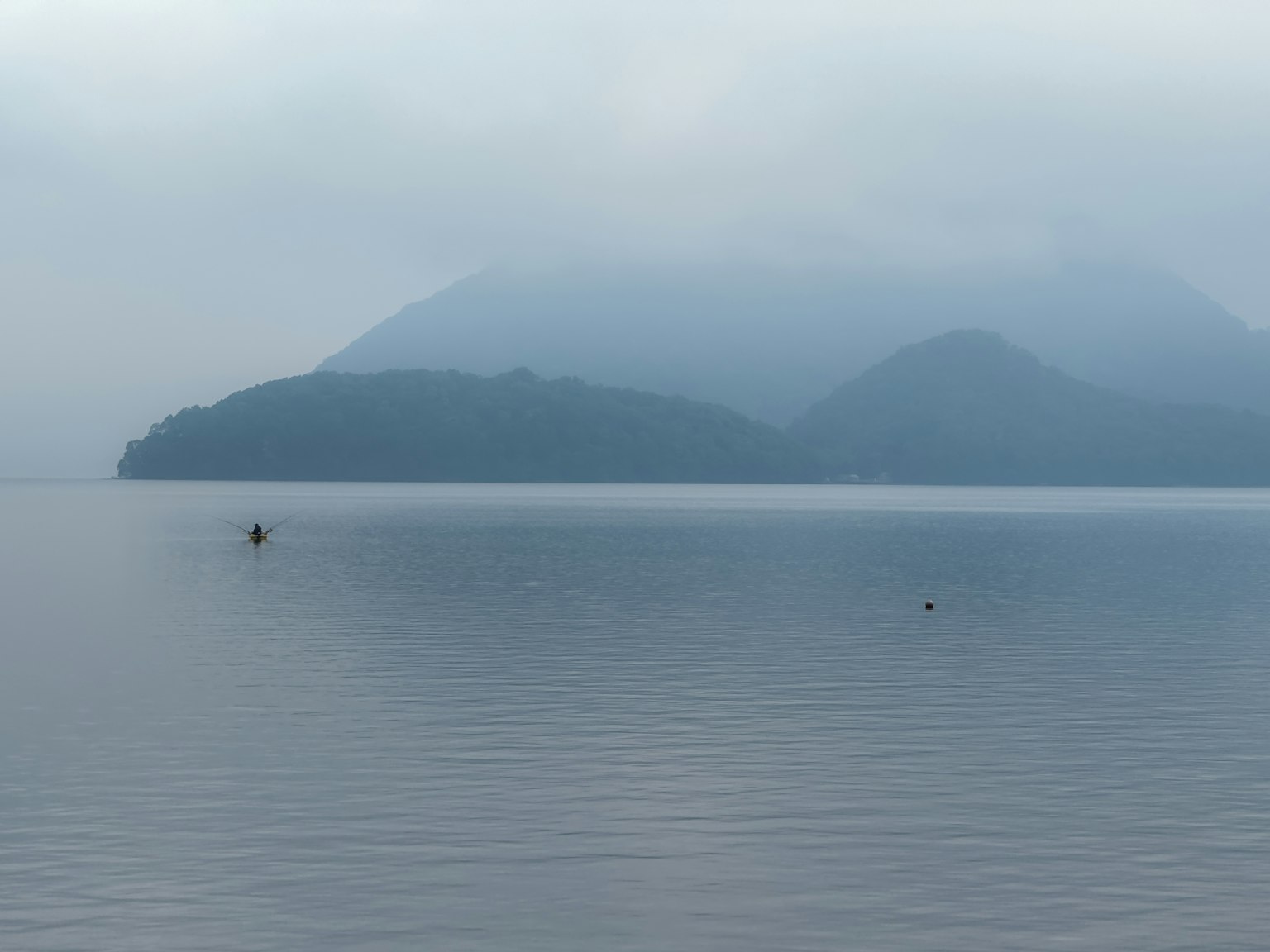 Lago calmo e montagne avvolte nella nebbia