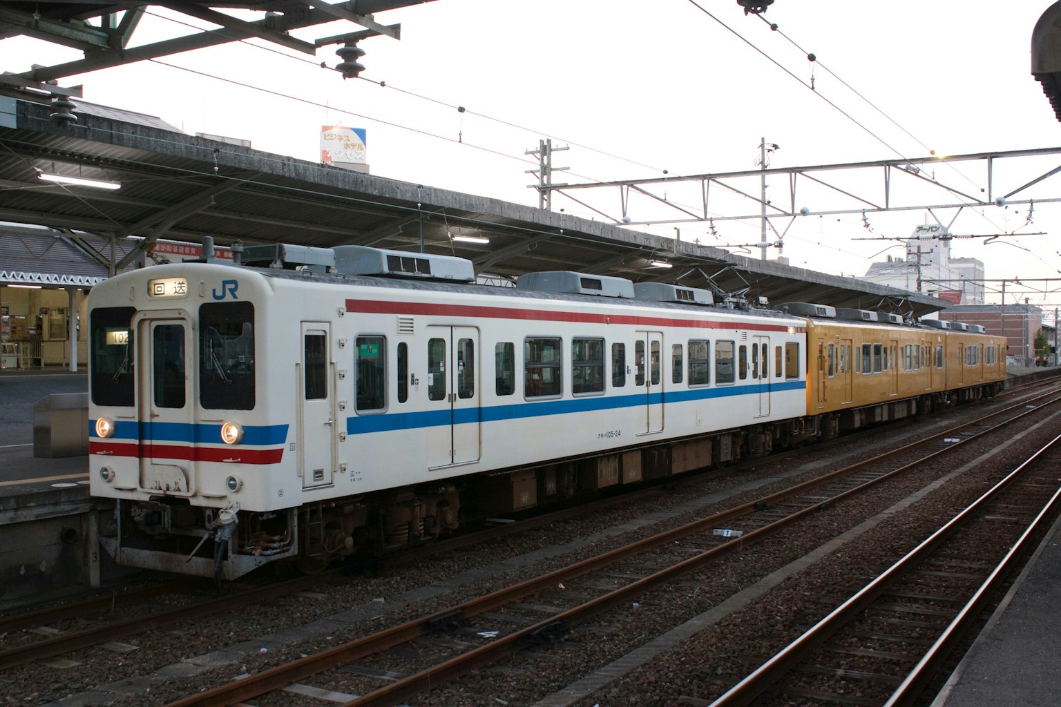 Treno bianco e blu con treno giallo in una stazione