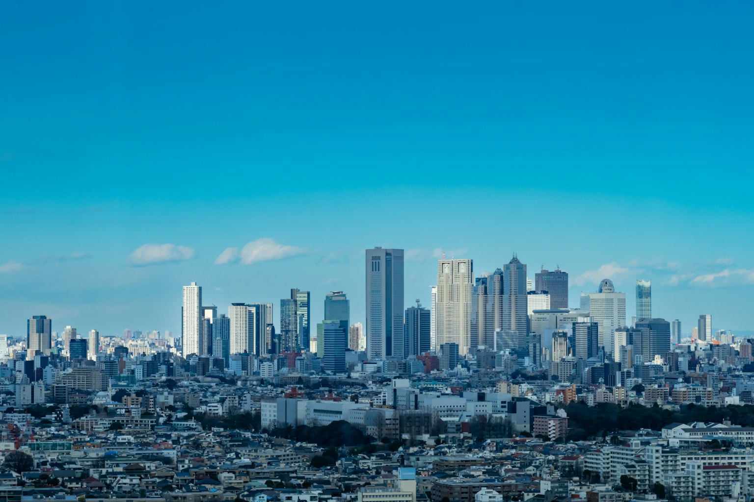 Skyline di Tokyo con grattacieli moderni sotto un cielo blu chiaro