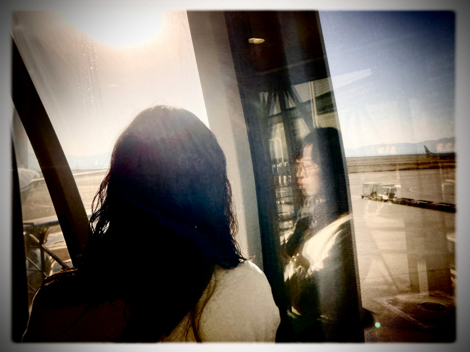 窓の外を見つめる女性のシルエットと反射がある風景