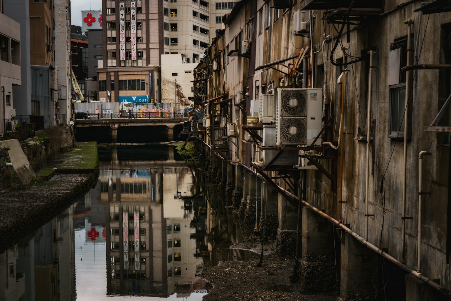 Narrow waterway with old buildings and reflections of air conditioning units on the walls