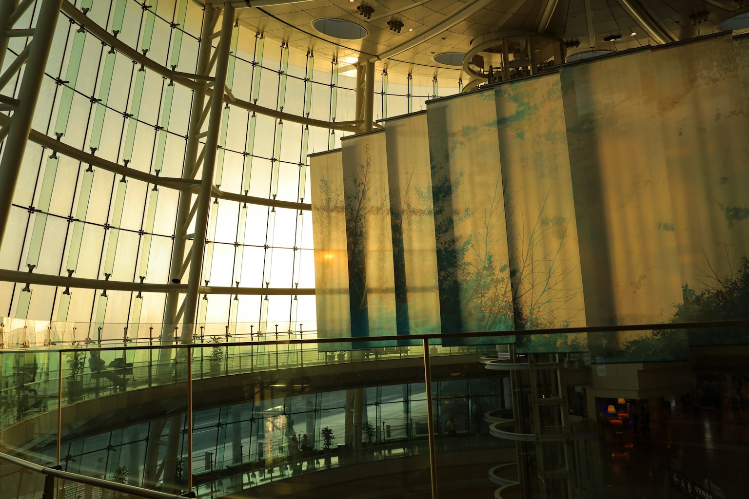 Interior bangunan modern dengan dinding kaca dan sinar matahari masuk