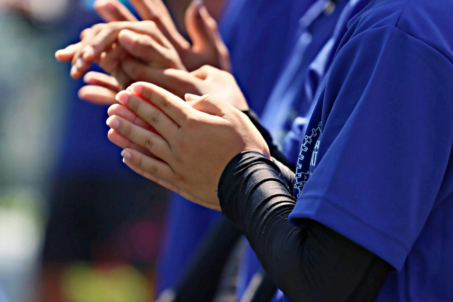 Tangan bertepuk tangan dari individu yang mengenakan baju biru