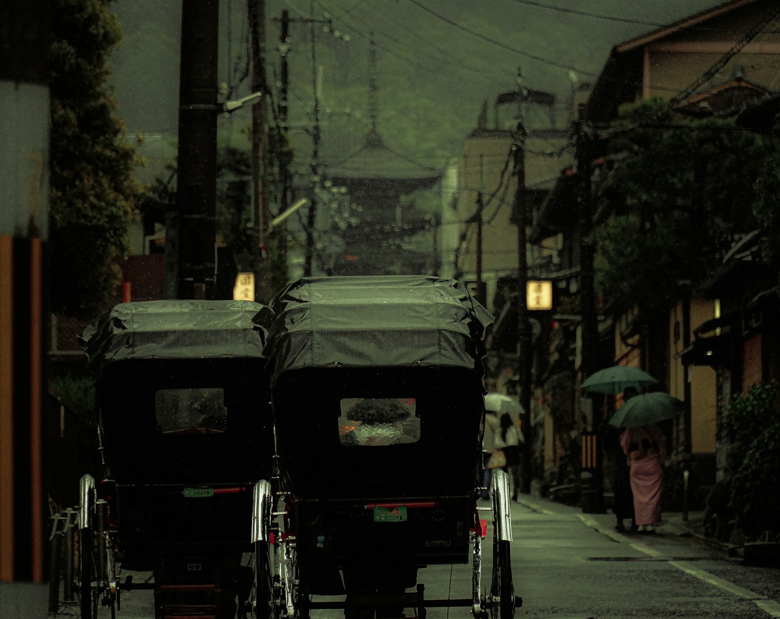 Two rickshaws on a dimly lit street surrounded by traditional buildings