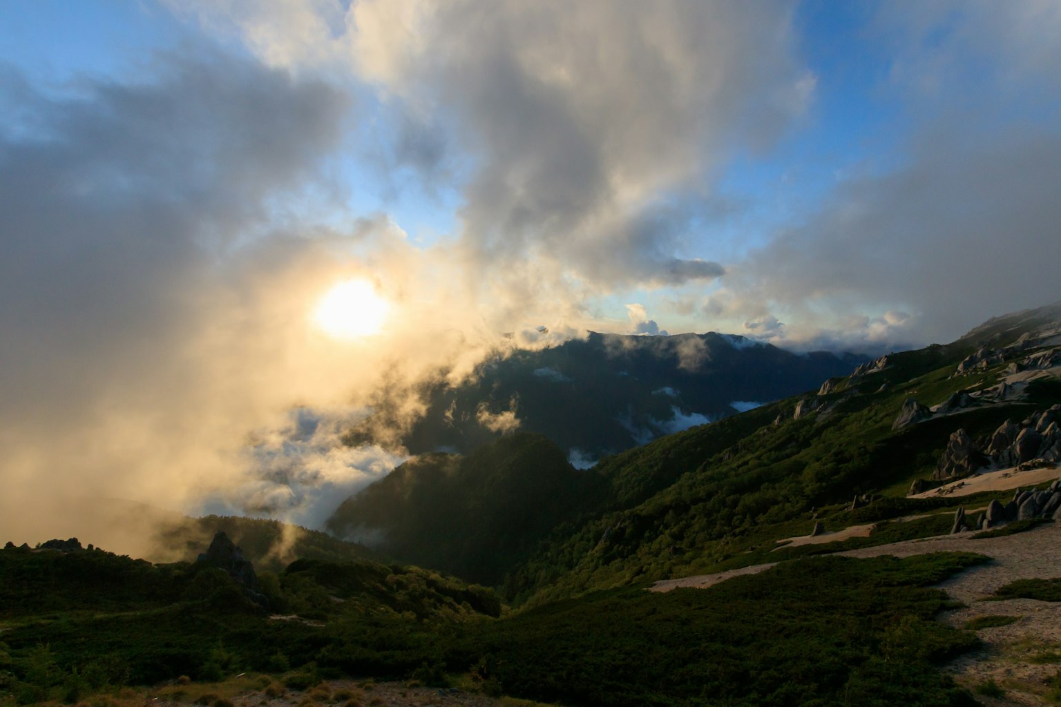 Pemandangan matahari terbenam di atas pegunungan dengan awan