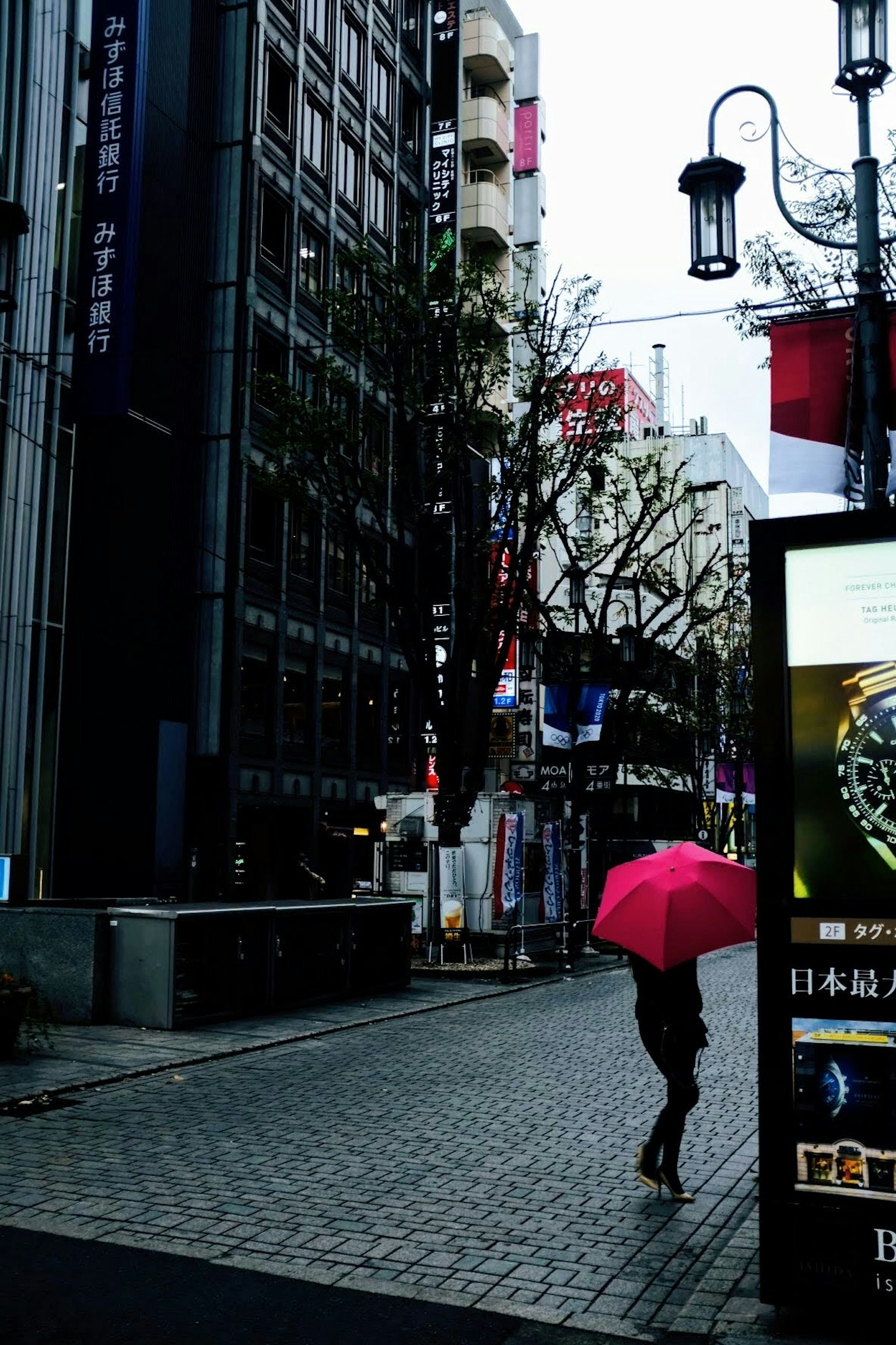 A city scene with a person walking under a pink umbrella in the rain