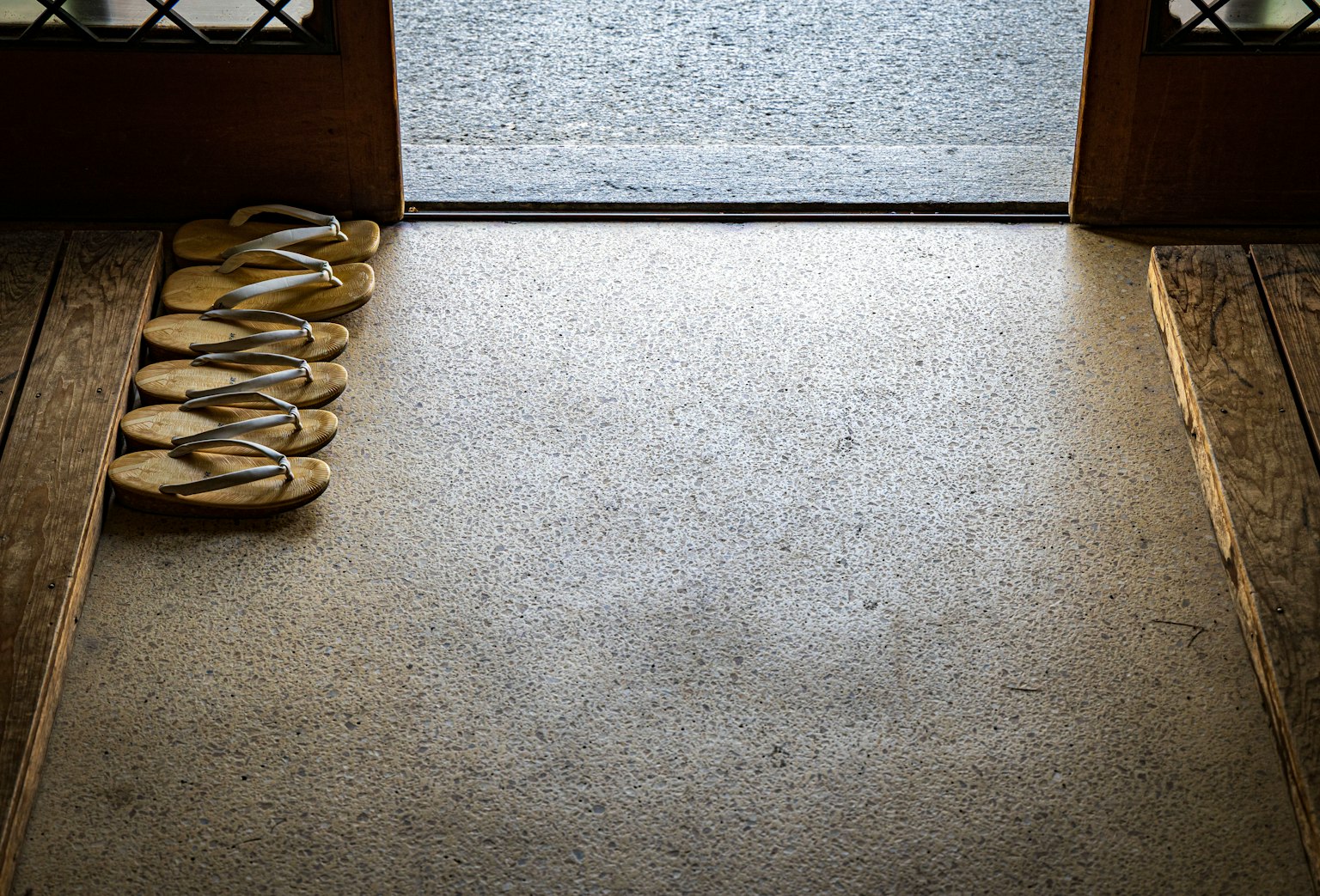 Immagine di sandali posizionati davanti a una porta in legno su un pavimento in pietra
