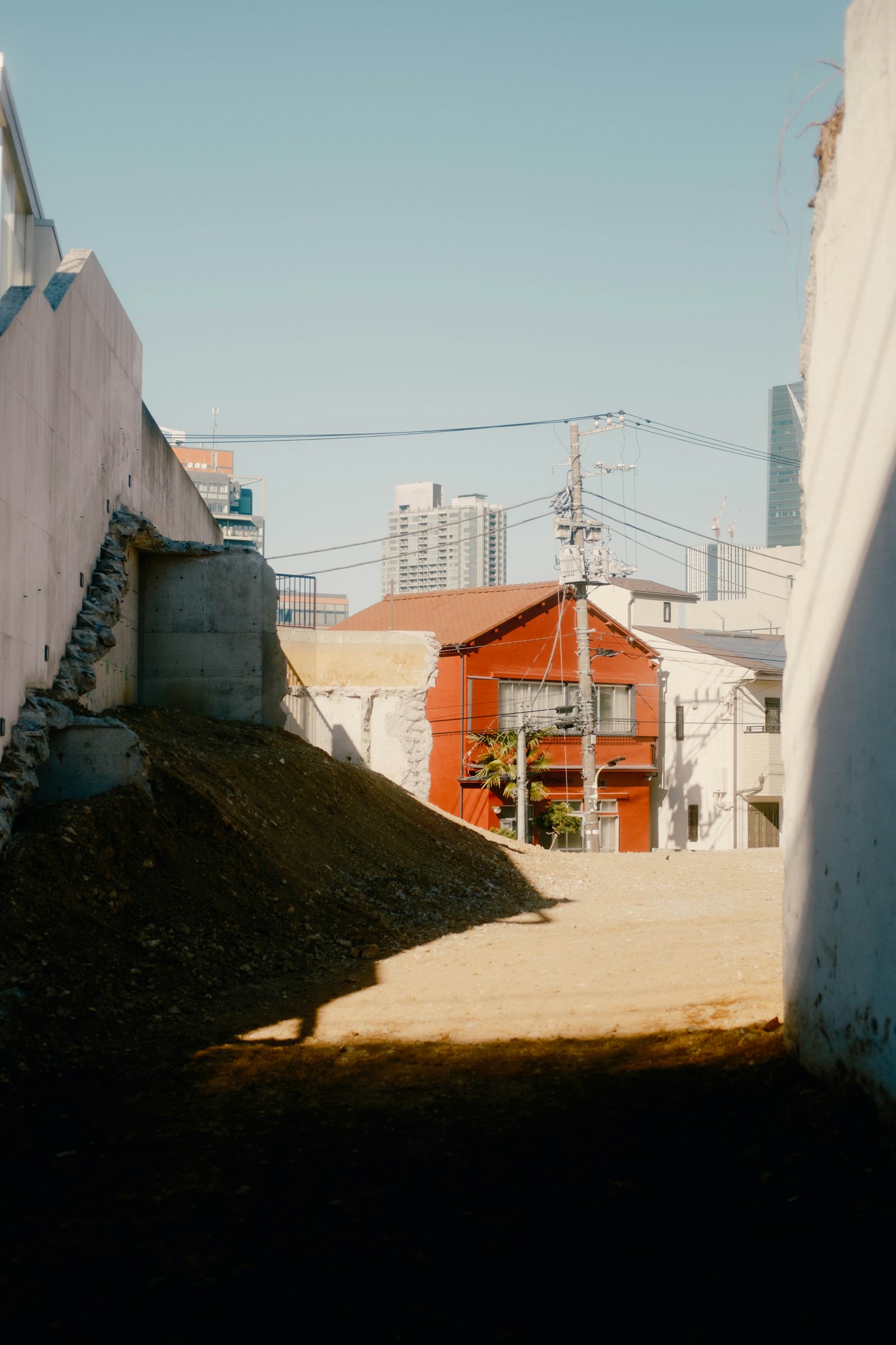 Narrow alleyway revealing a red house in the distance