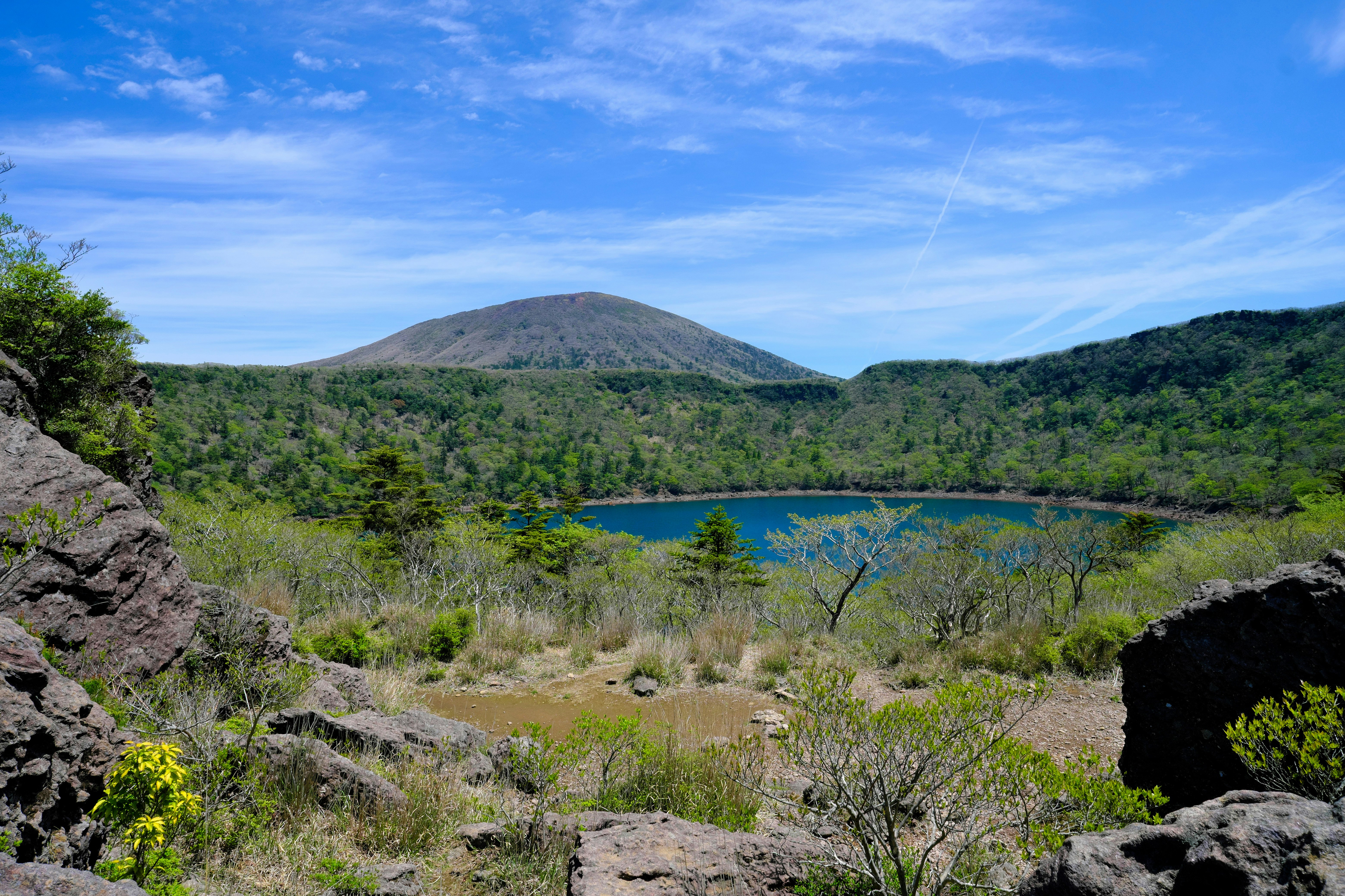 岩の間から見渡す森と湖、遠くに山のある景色