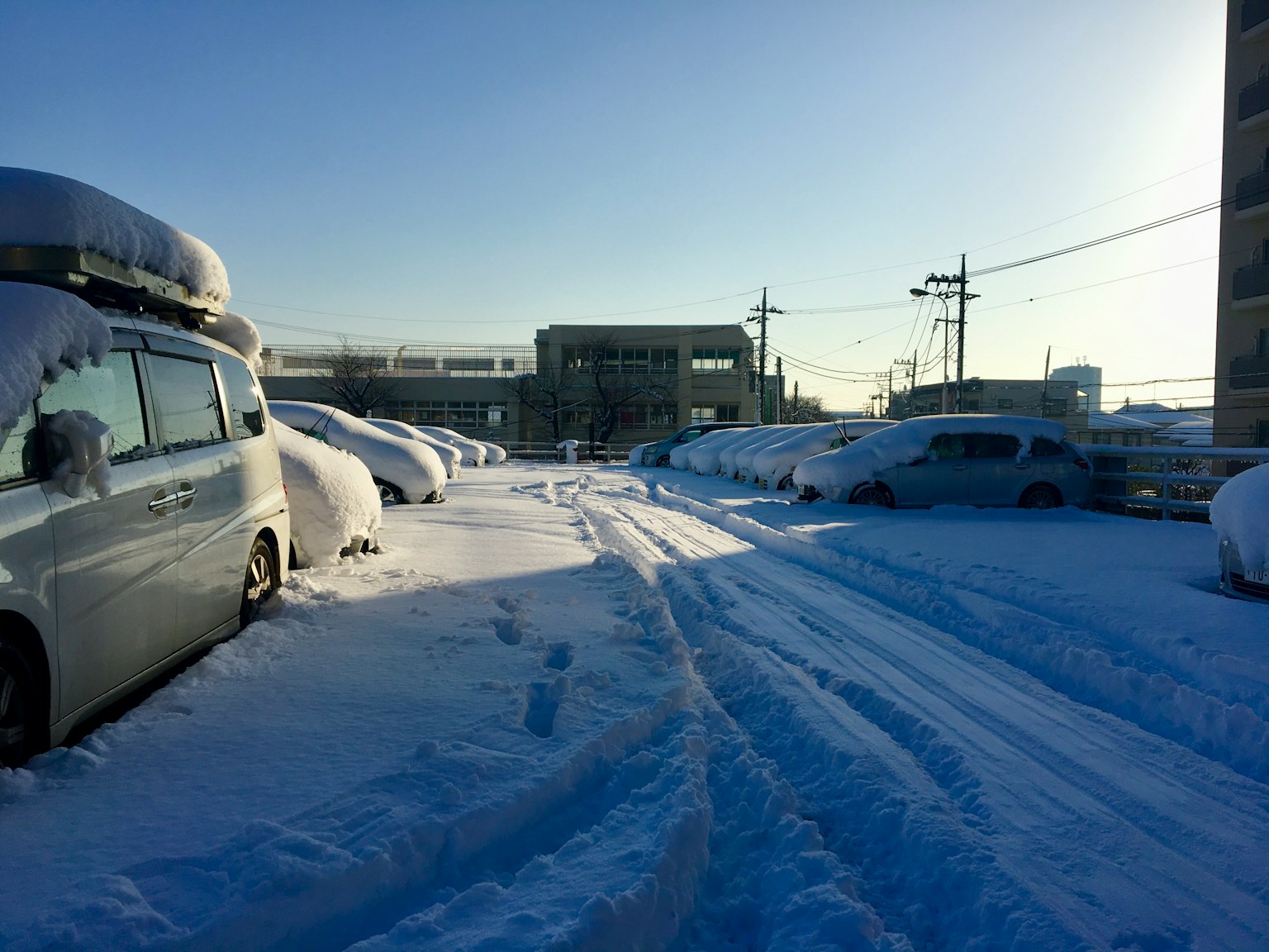 Scena di un parcheggio coperto di neve Auto coperte di neve e cielo blu