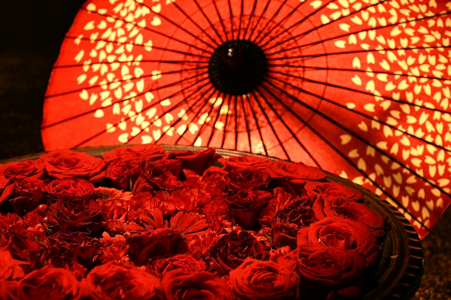 Red roses arranged on a plate with a decorative red umbrella in the background