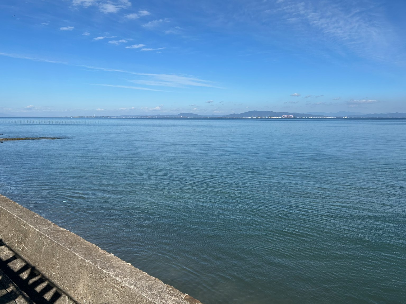 Paysage de mer calme et ciel bleu avec une jetée en béton au premier plan