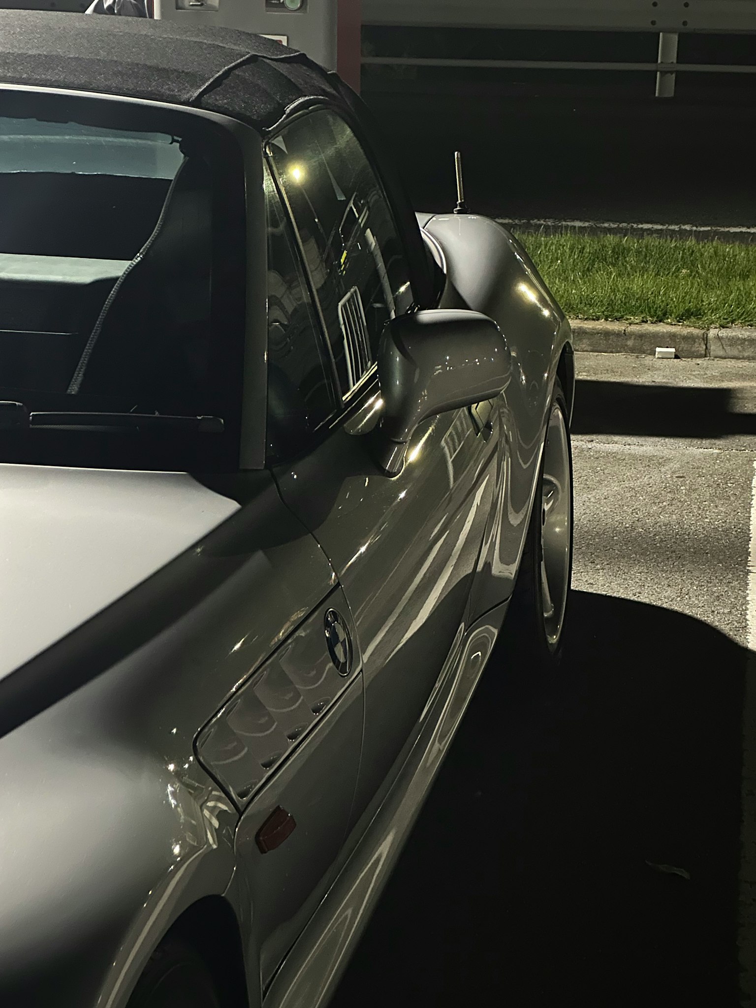 Shiny silver sports car side view in a nighttime parking lot
