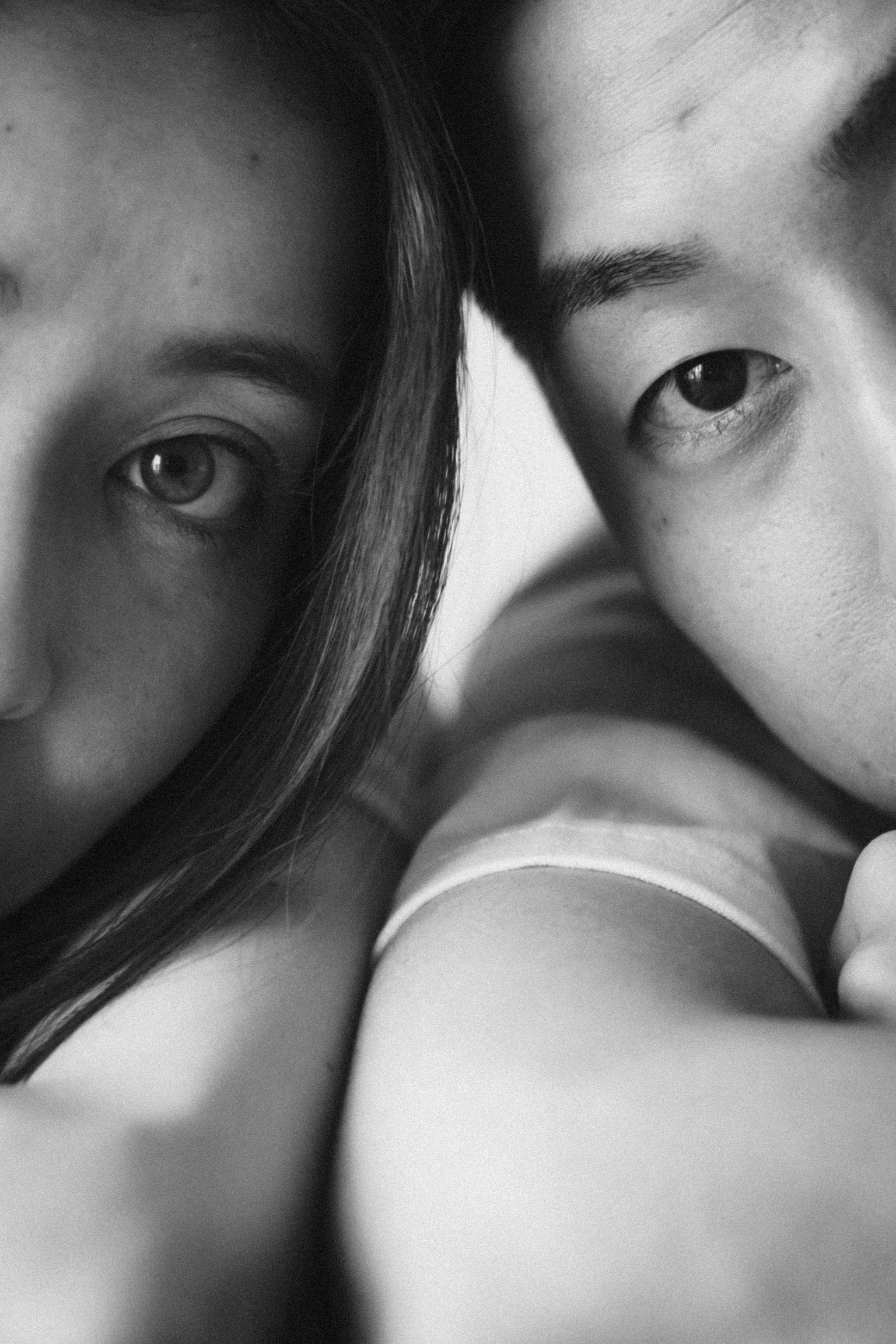 Close-up monochrome portrait of two individuals with a focus on their eyes and facial features