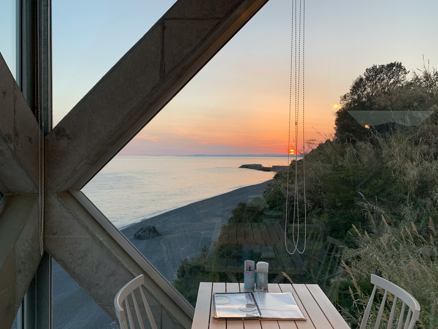 Gemütlicher Esstisch mit Stühlen mit Blick auf einen Sonnenuntergang am Strand