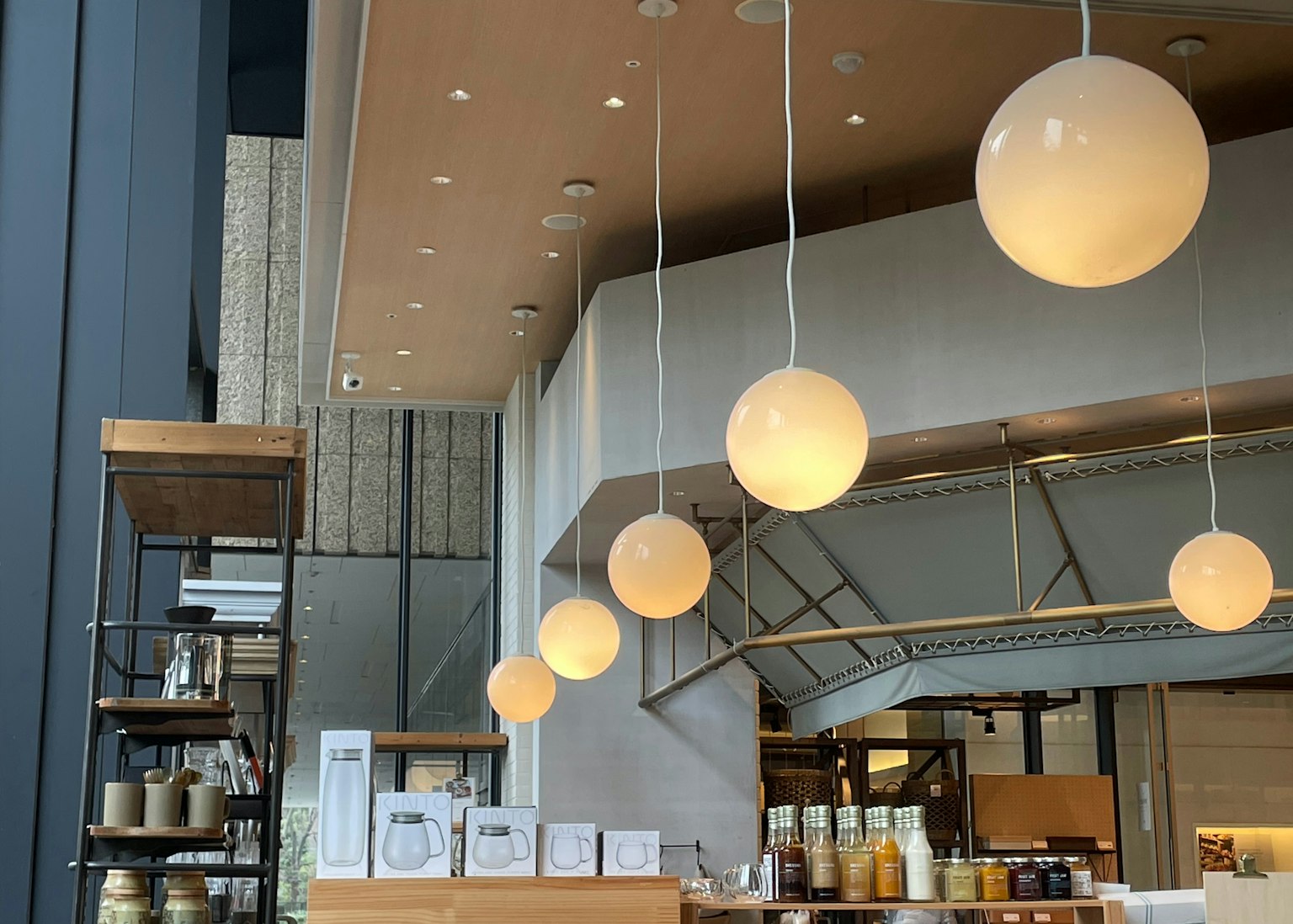 Design interno di un caffè moderno con lampade a sospensione rotonde bancone in legno e scaffali atmosfera elegante e minimalista