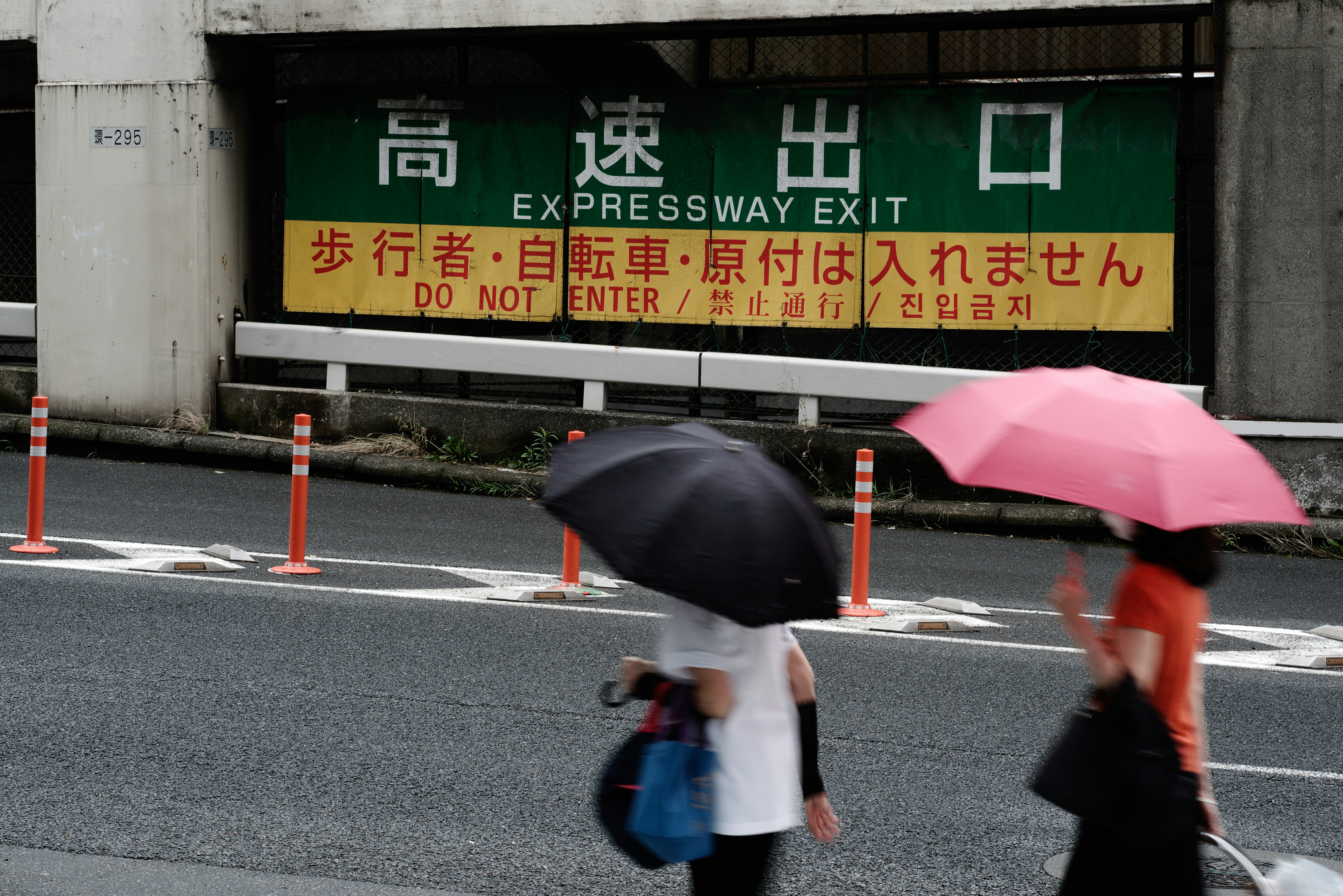 高速公路出口指示牌前打伞的人