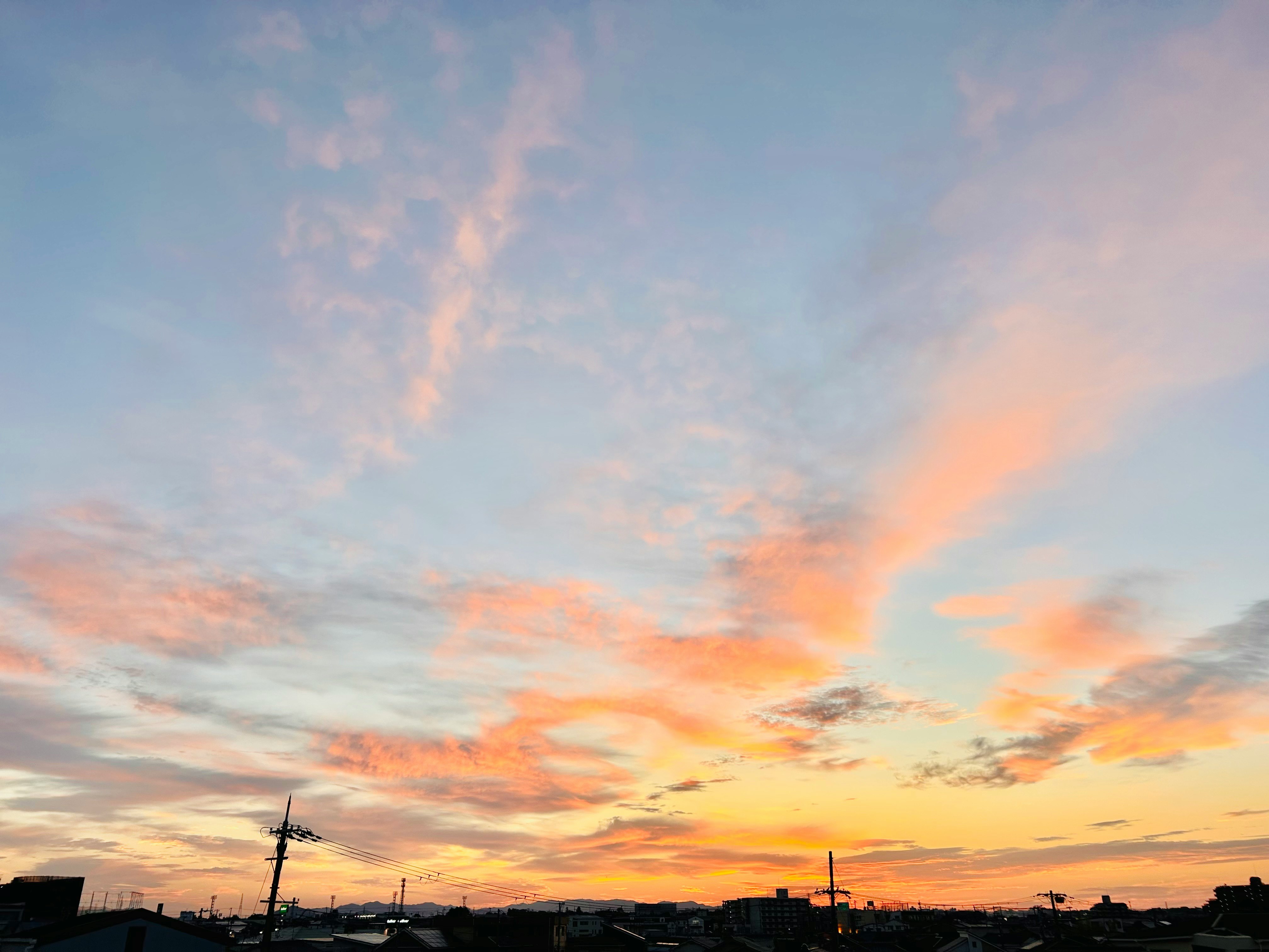 Wolken über einem Sonnenuntergangshimmel mit einer silhouettierten Stadtsilhouette