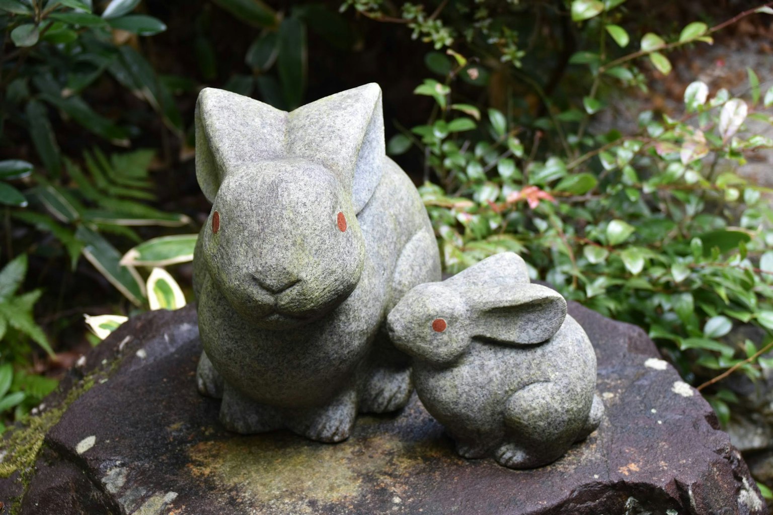 Dua patung kelinci batu duduk bersama di taman