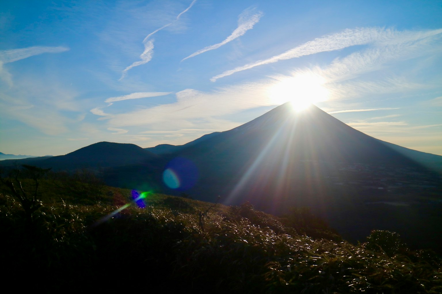 Sonnenlicht, das vom Gipfel eines Berges gegen einen blauen Himmel strahlt